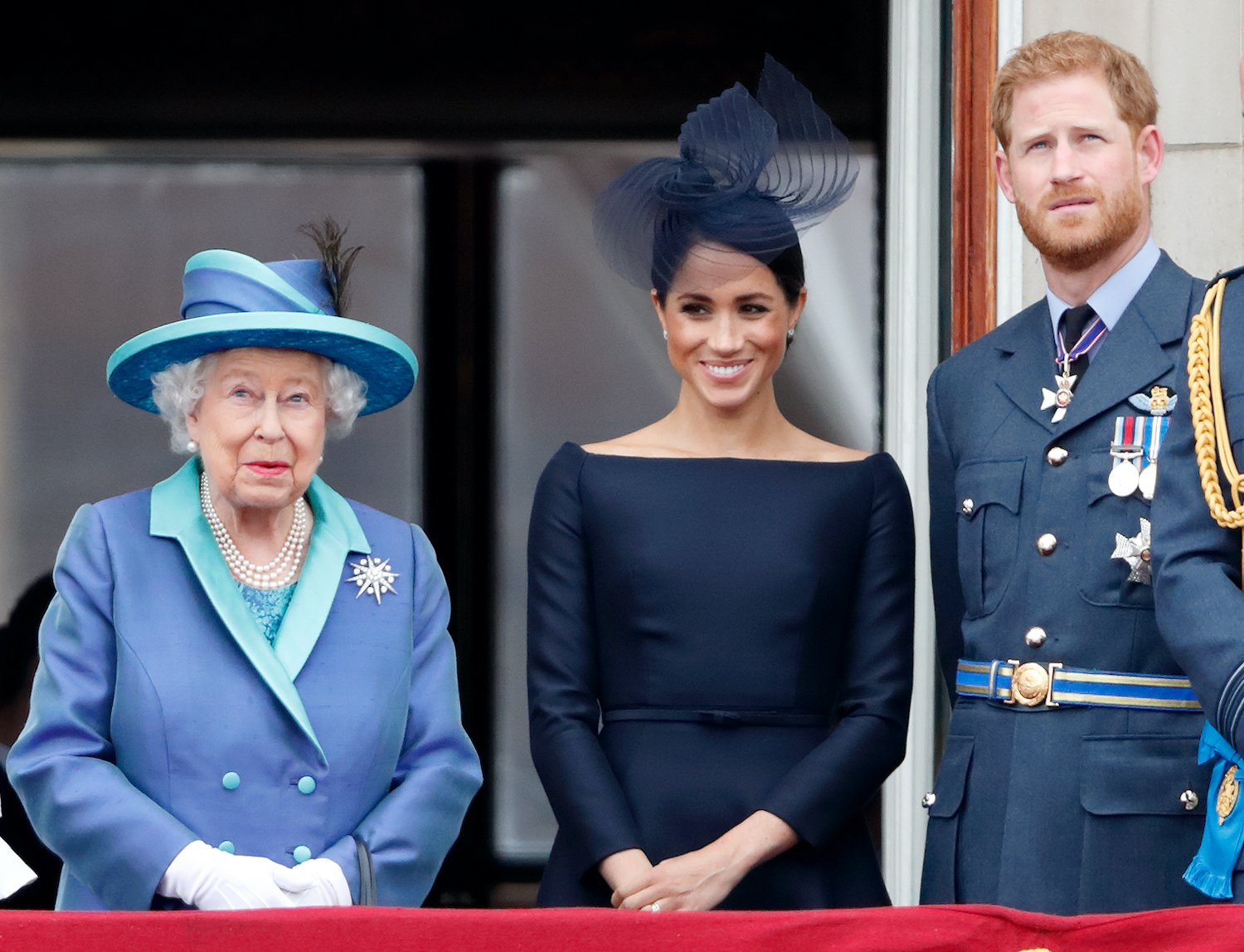 Queen Elizabeth II, Meghan Markle, and Prince Harry watch a flypast to mark the centenary of the Royal Air Force from the balcony of Buckingham Palace