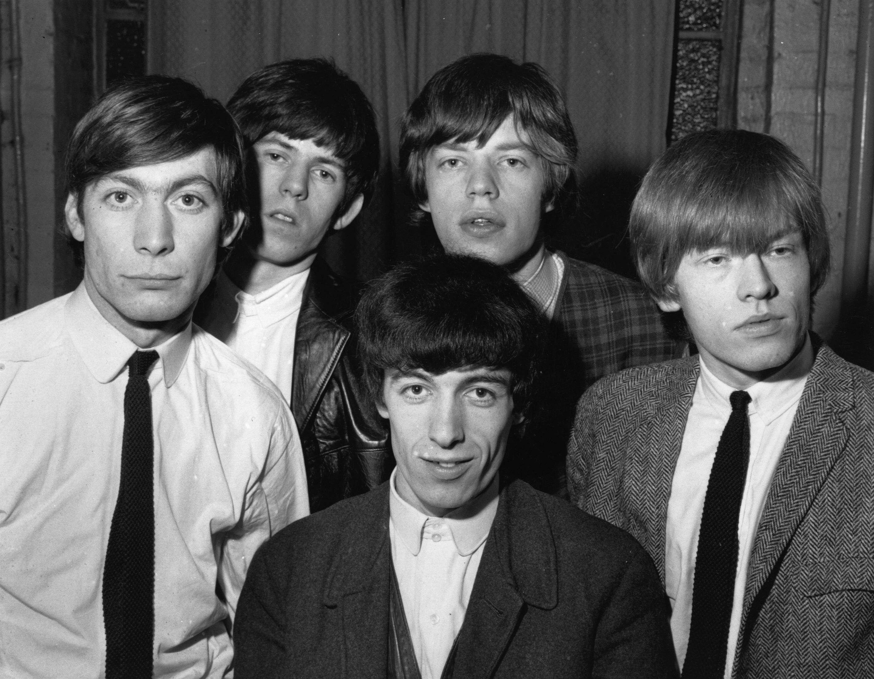 The Rolling Stones standing in front of a curtain