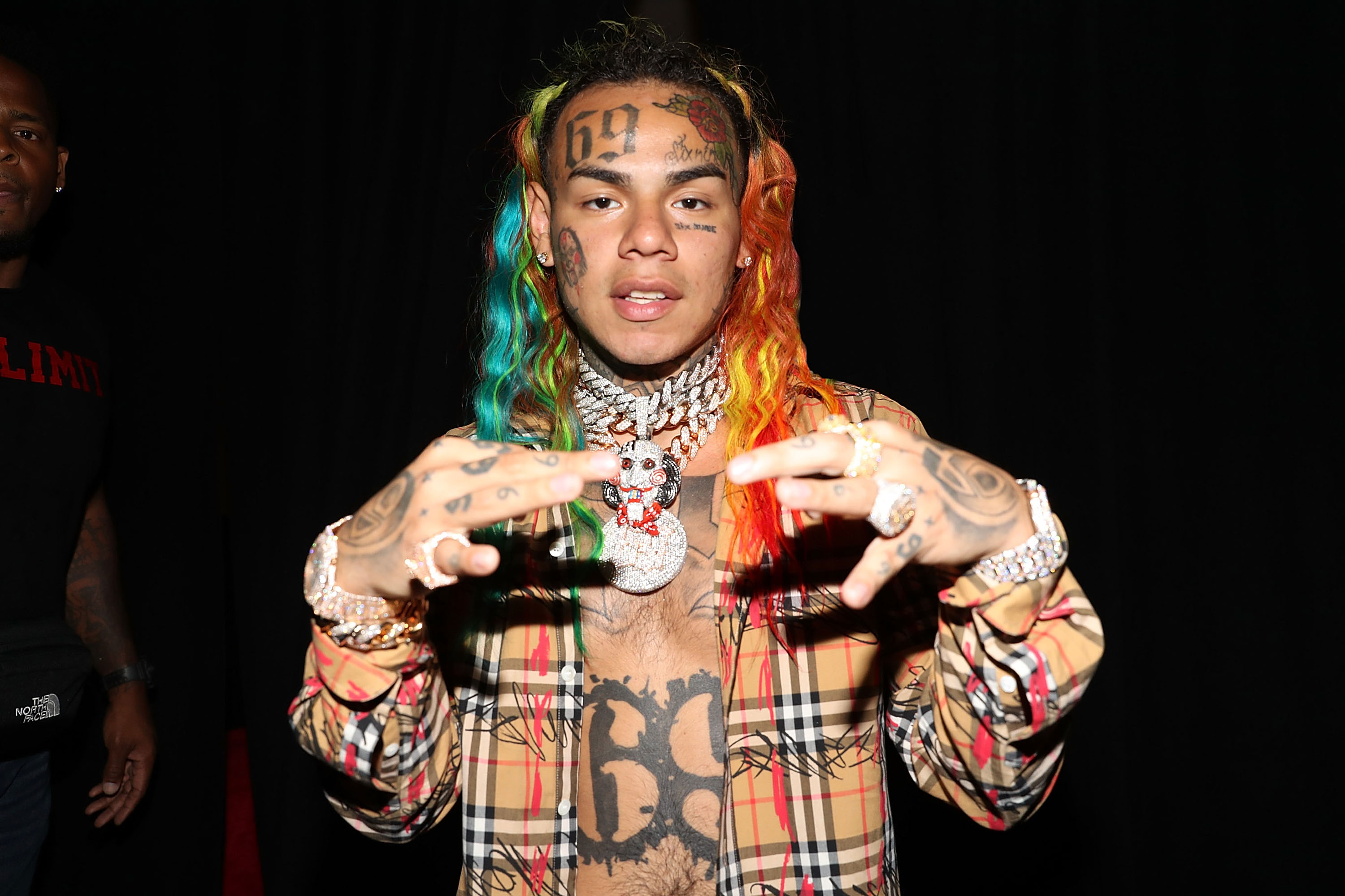 Tekashi 6ix9ine wearing a necklace depicting Billy the Puppet from Saw