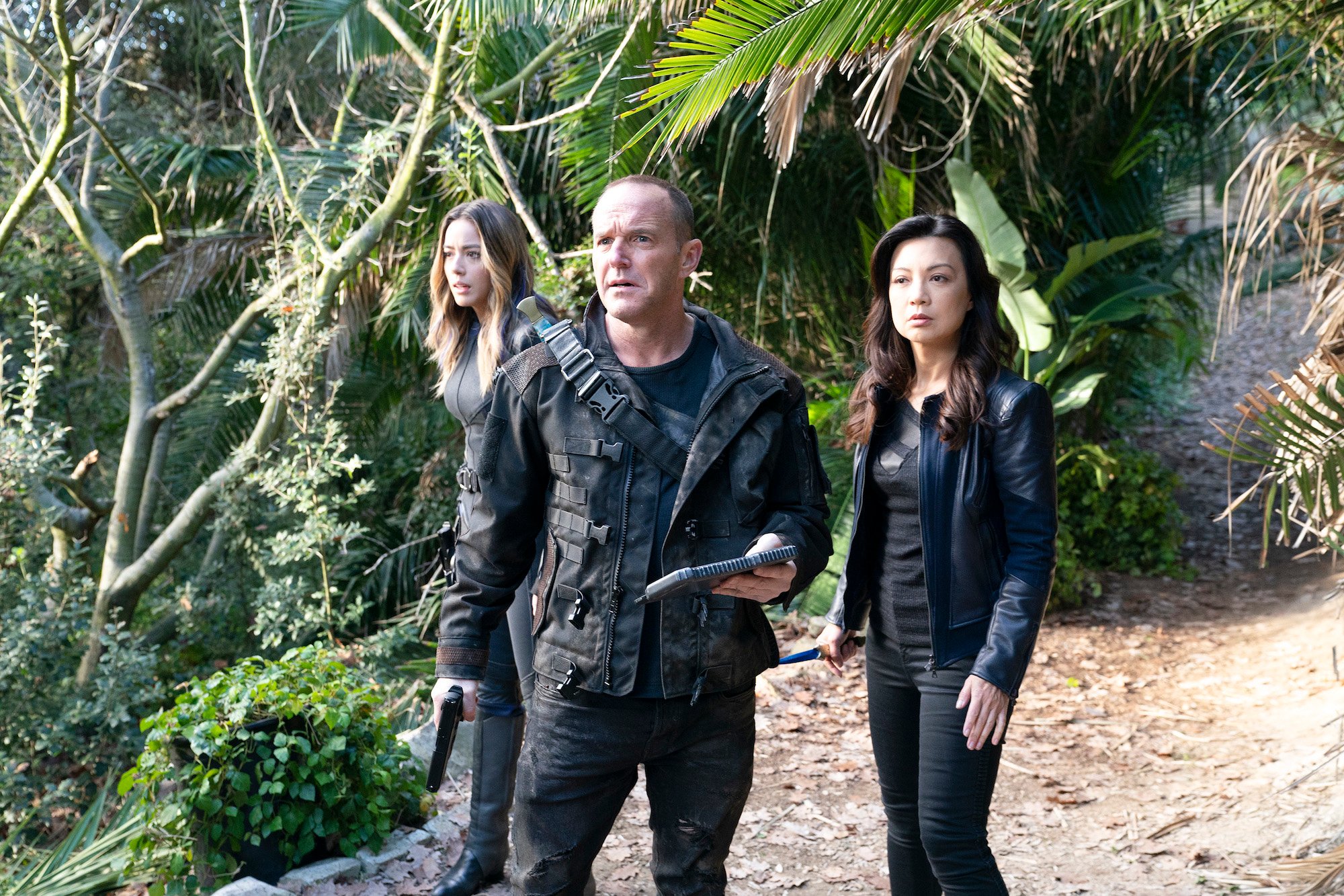 Chloe Bennet, Clark Gregg, Ming-Na Wen on a path surrounded by greenery