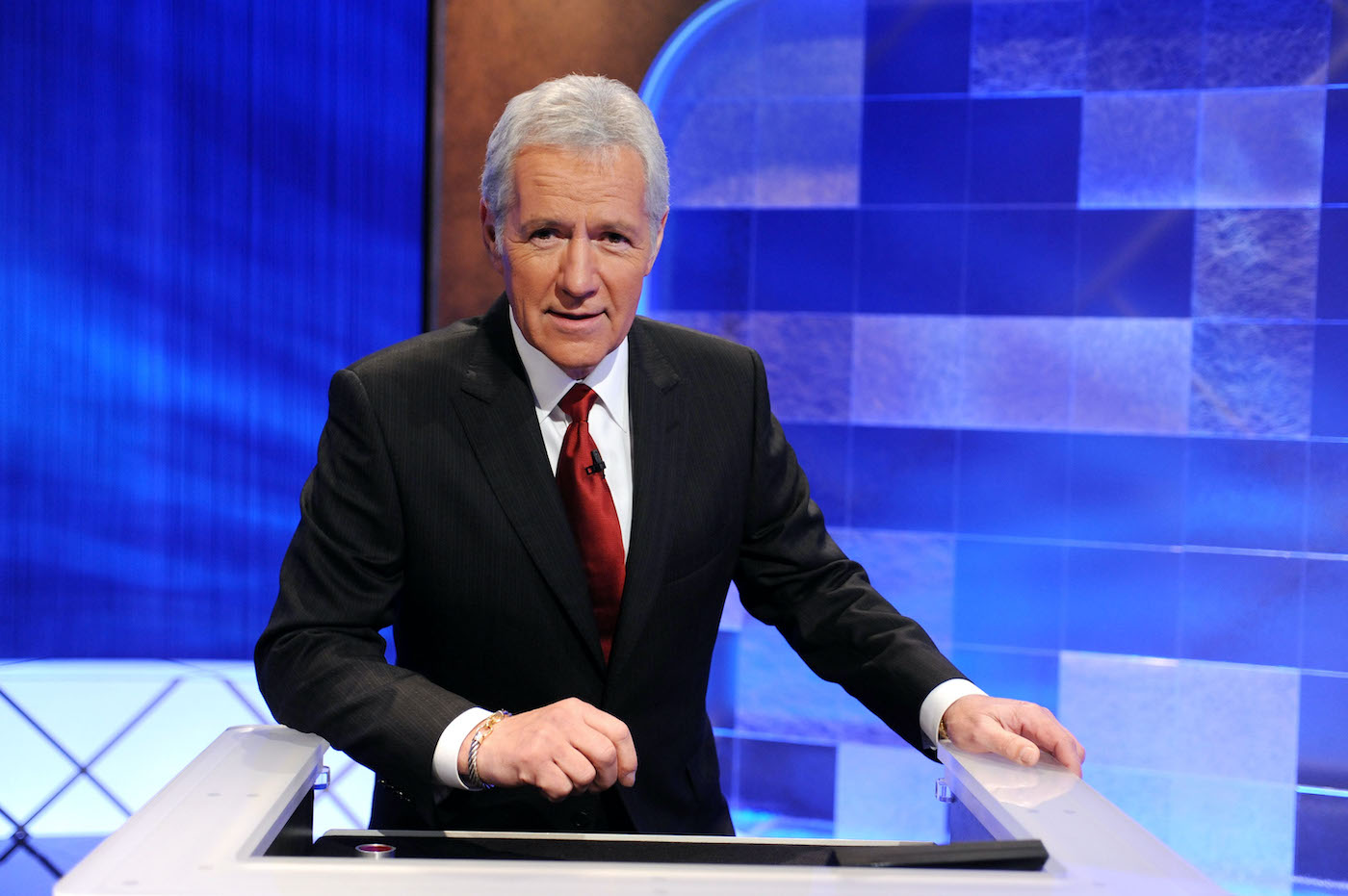 Alex Trebek stands behind a podium on the set of 'Jeopardy!' 