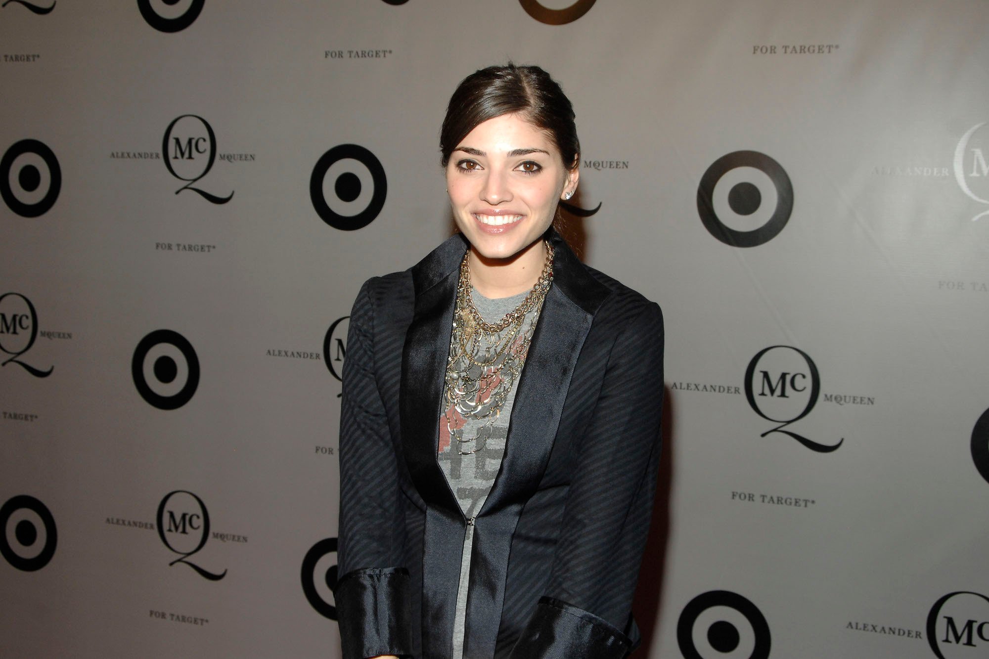 Amanda Setton smiling in front of a white background, smiling