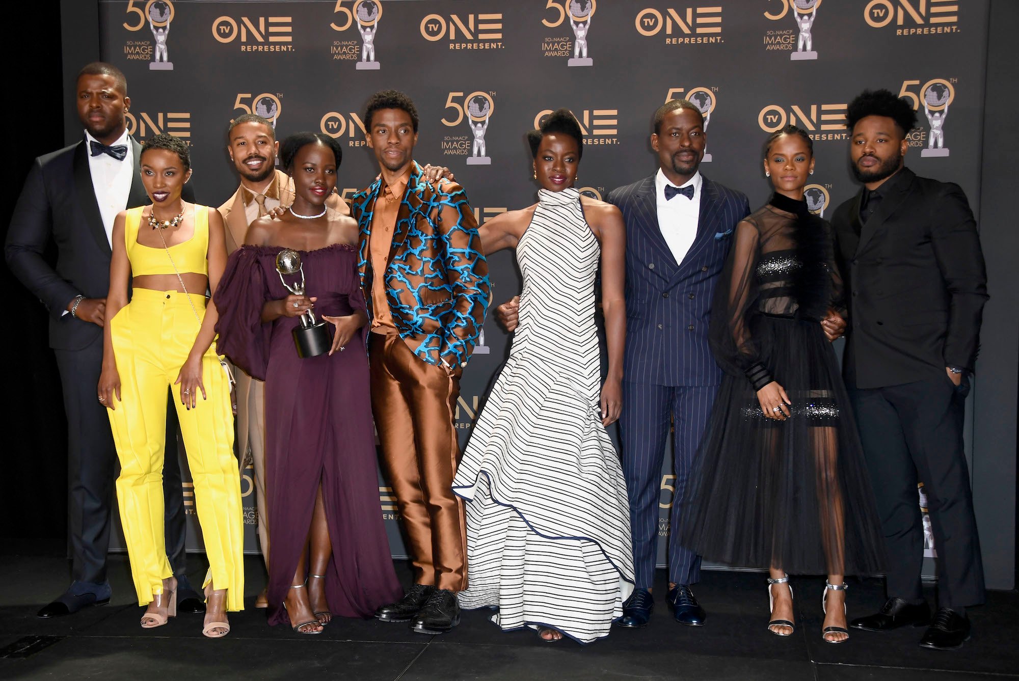 (L-R) Winston Duke, Carrie Bernans, Michael B. Jordan, Lupita Nyong'o, Chadwick Boseman, Danai Gurira, Sterling K. Brown, Letitia Wright, and Ryan Coogler in front of a black background