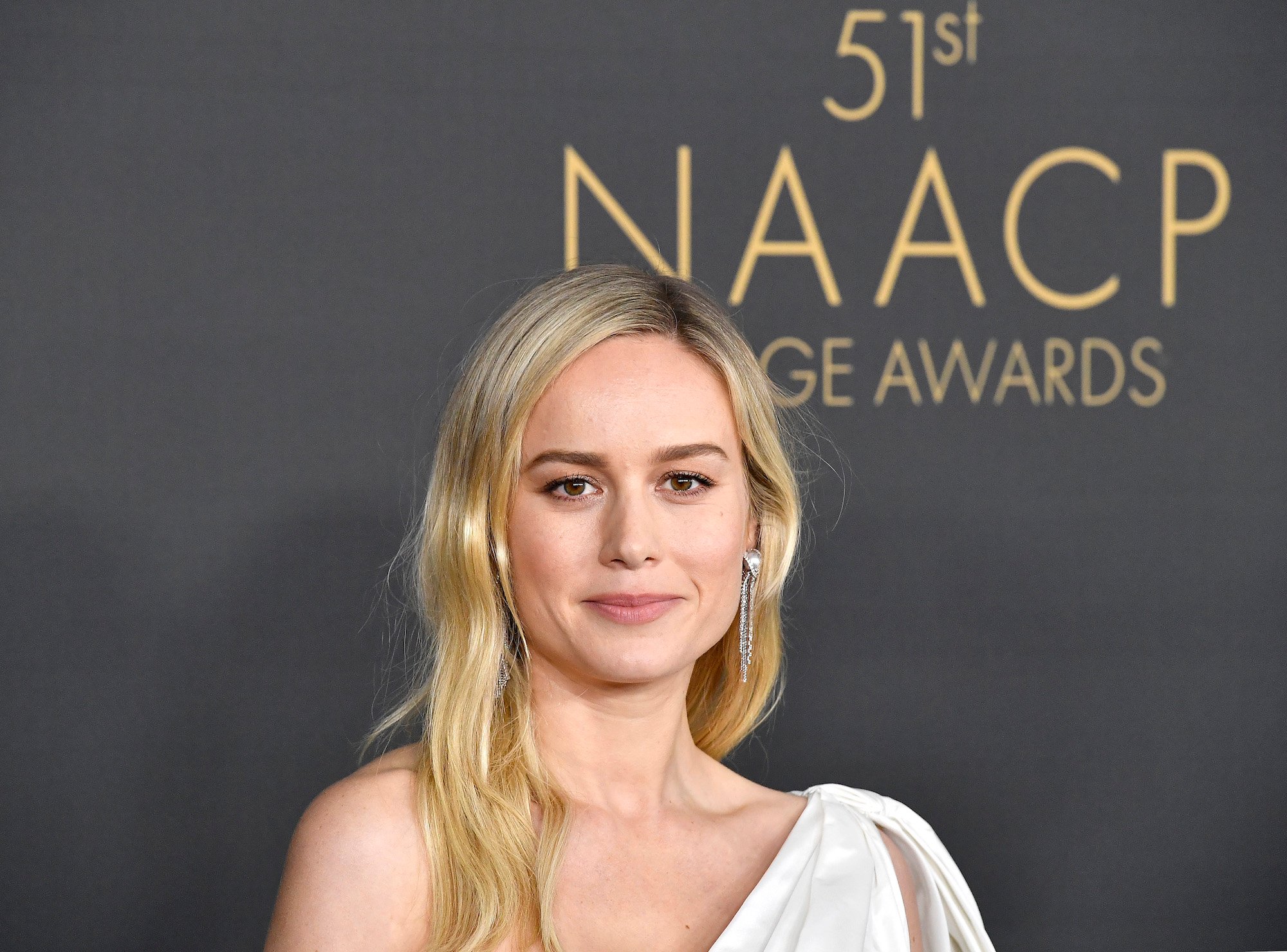 Brie Larson smiling in front of a dark background