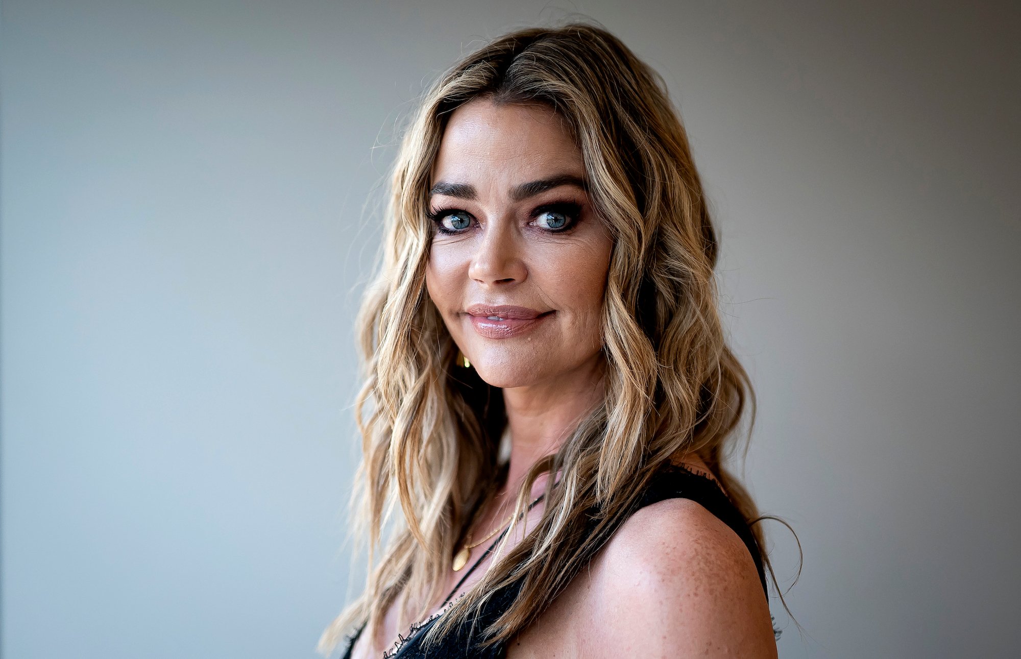 Denise Richards smiling at the camera, turned to the side