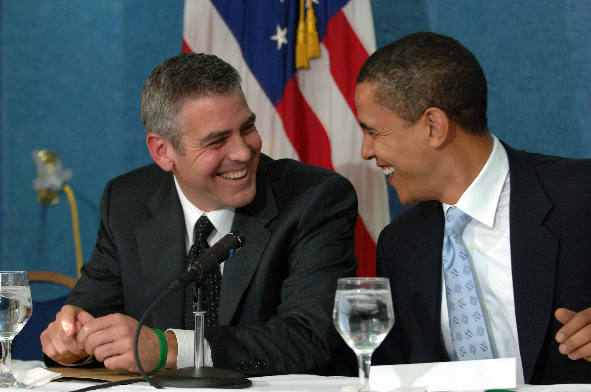 George Clooney and Barack Obama looking at each other laughing