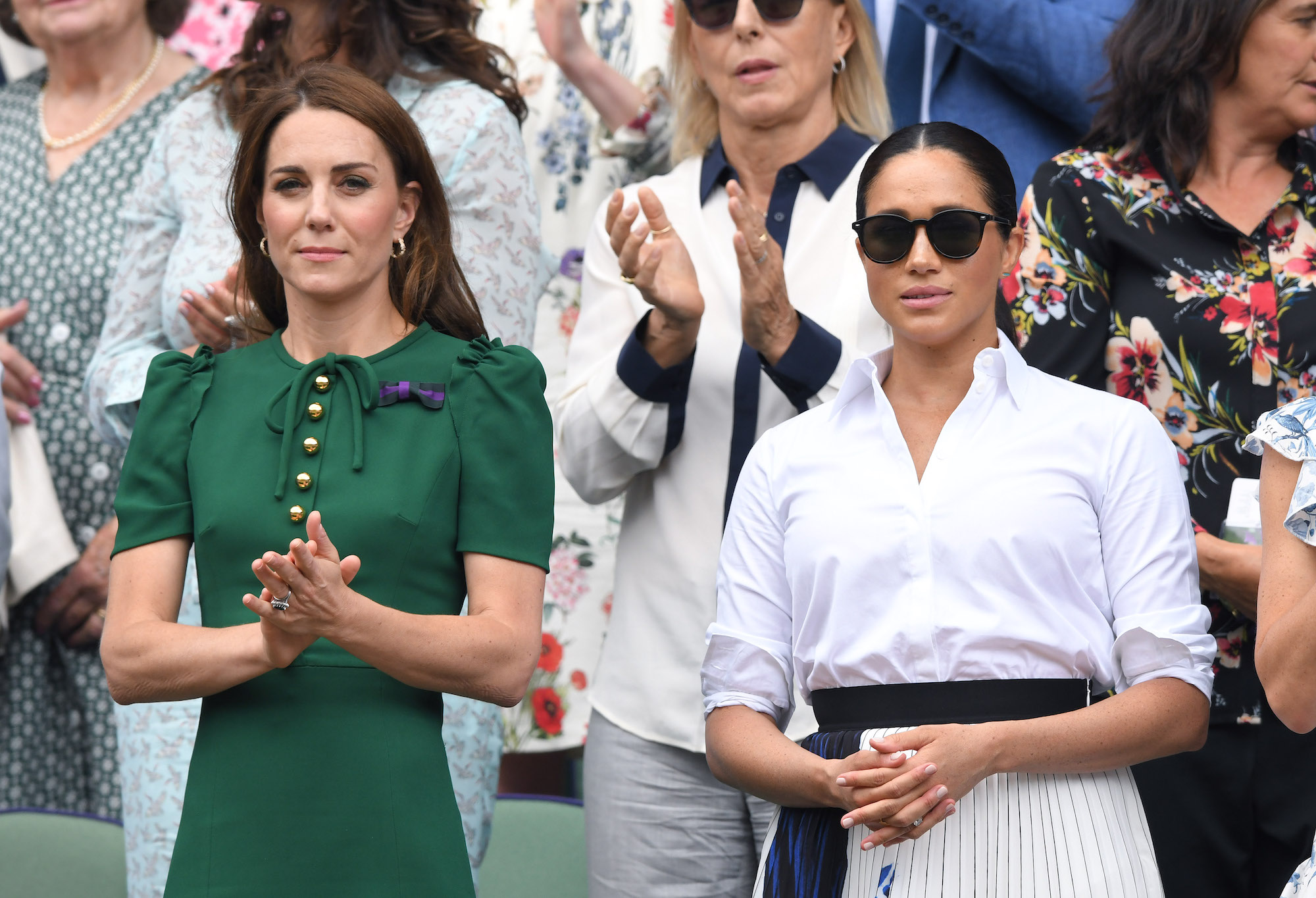 Kate Middleton and Meghan Markle standing next to each other, not smiling