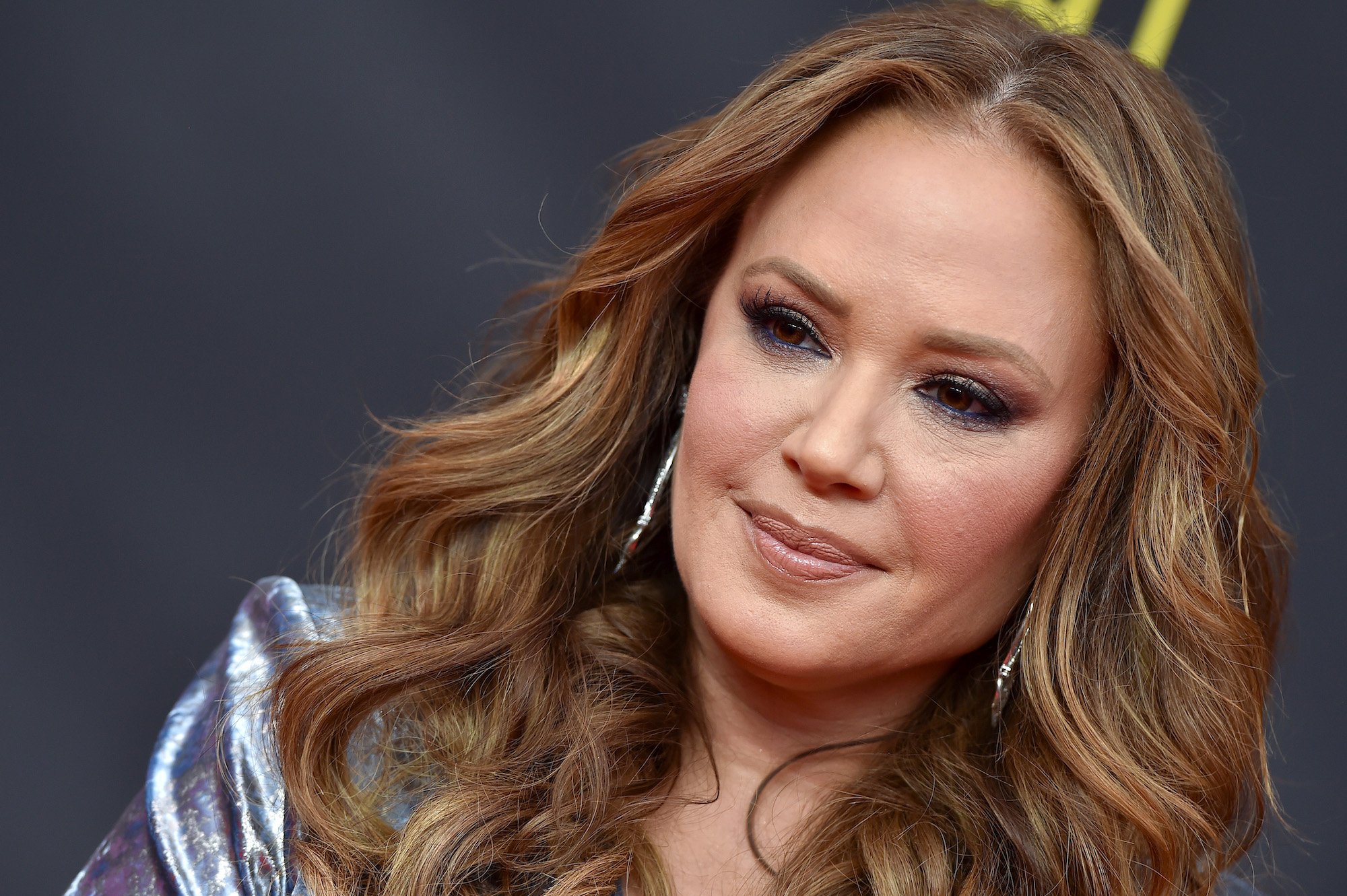 Leah Remini smiling in front of a dark background