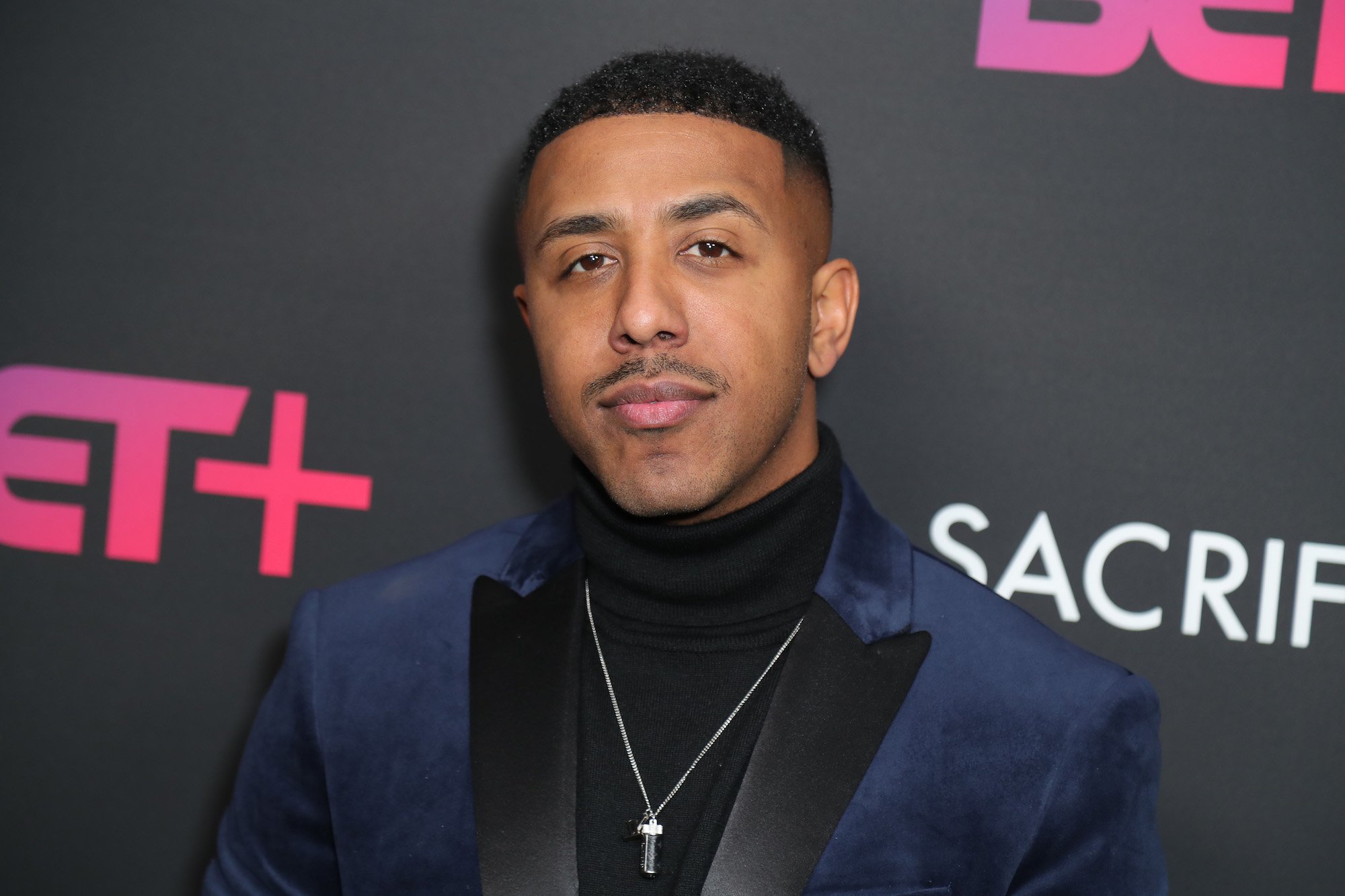 Marques Houston smiling in front of a black wall