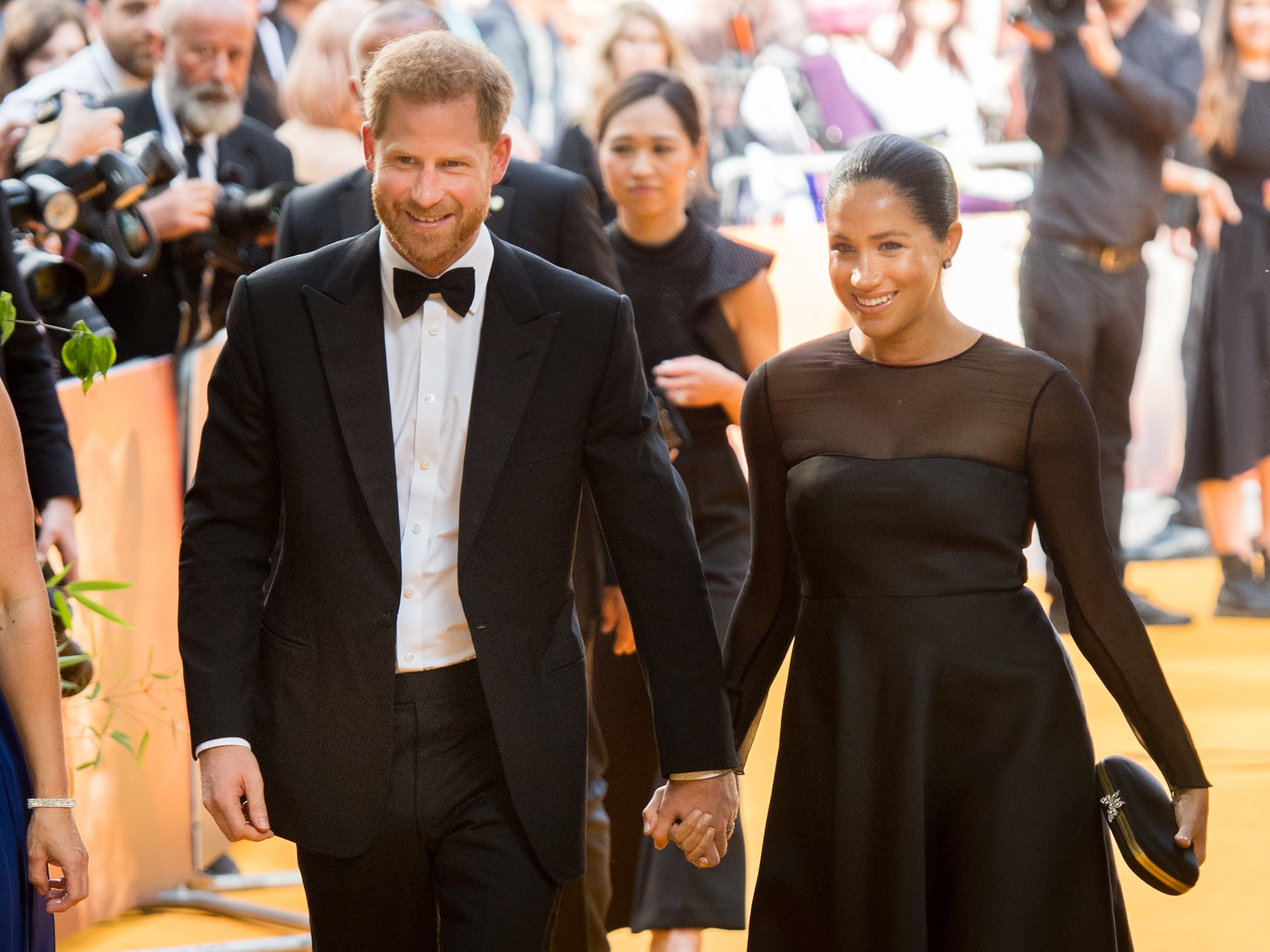 Prince Harry and Meghan Markle smiling, holding hands