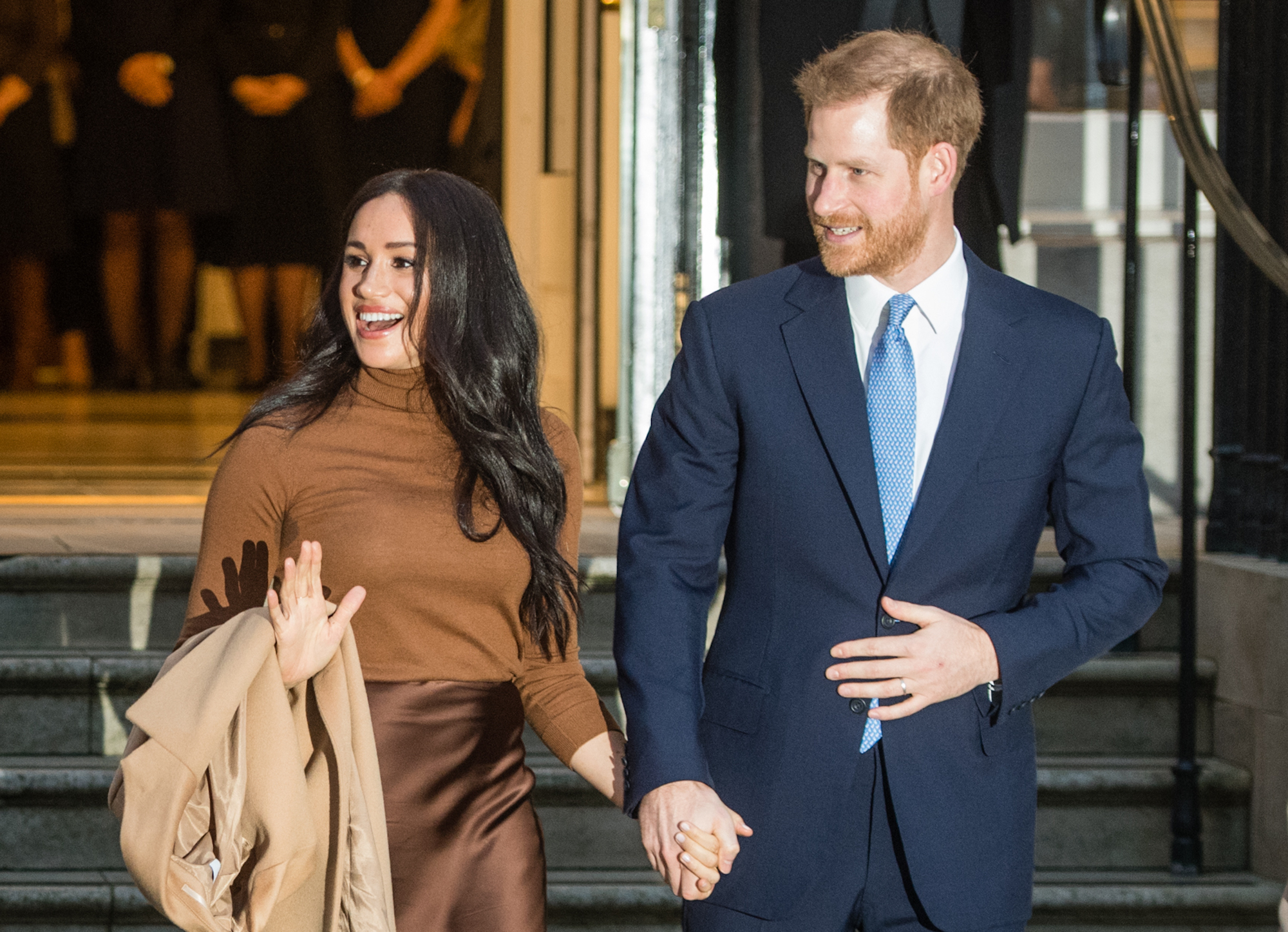Meghan Markle and Prince Harry, smiling, turned to the side