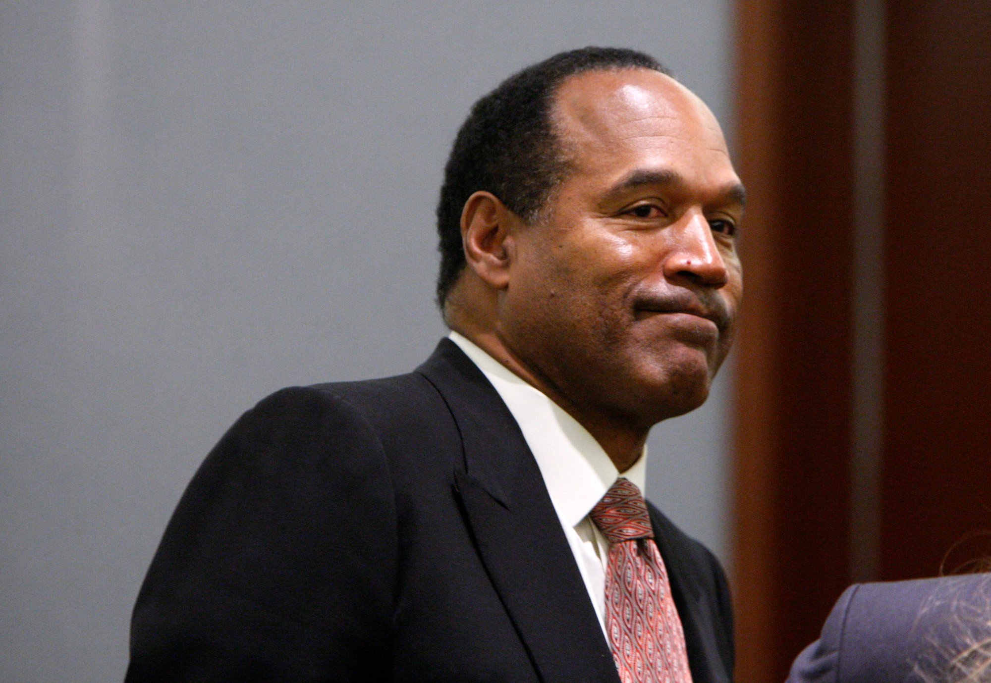 O.J. Simpson looking away from the camera in front of a gray wall