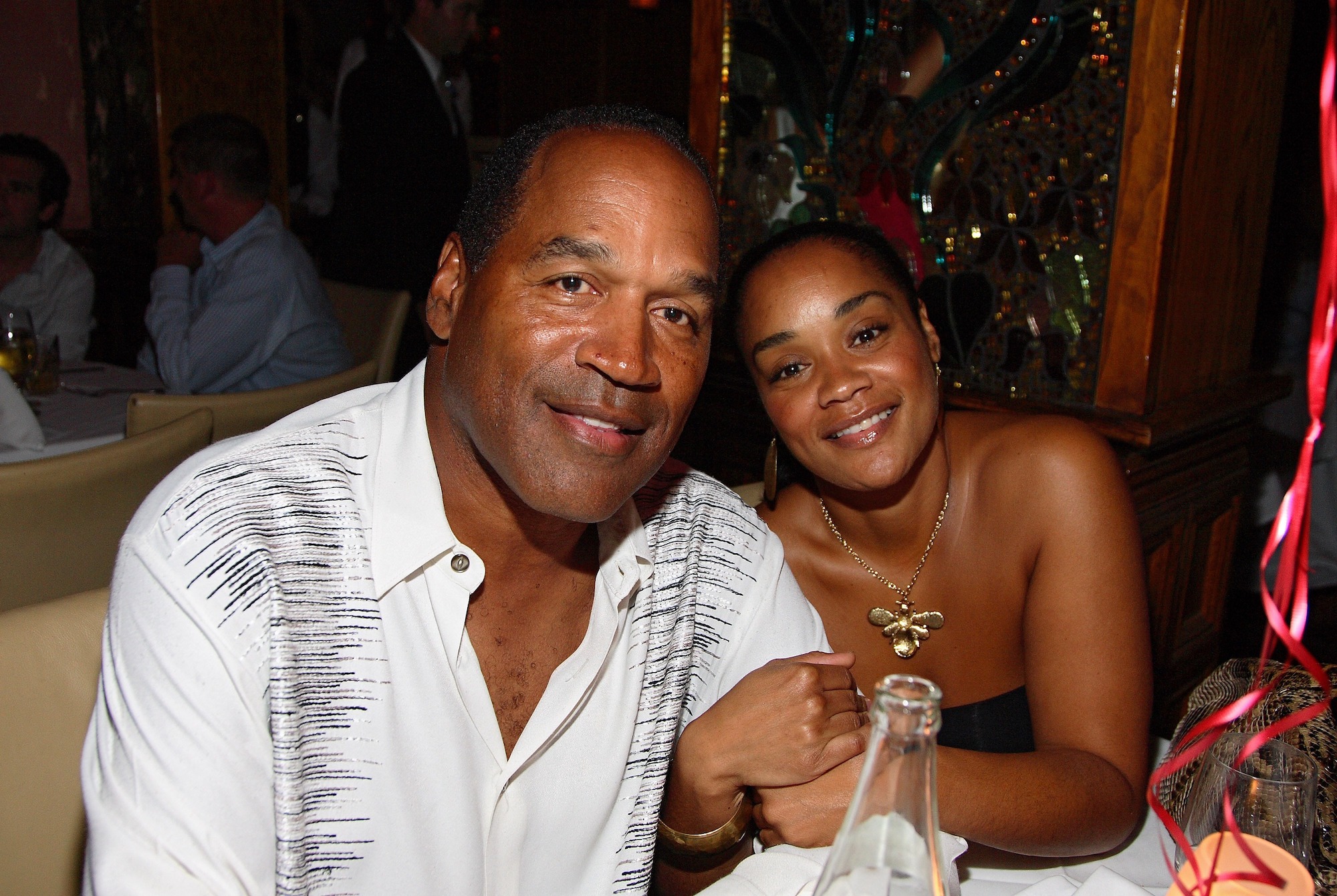 (L-R) O.J. Simpson and Arnelle Simpson smiling at a dinner table
