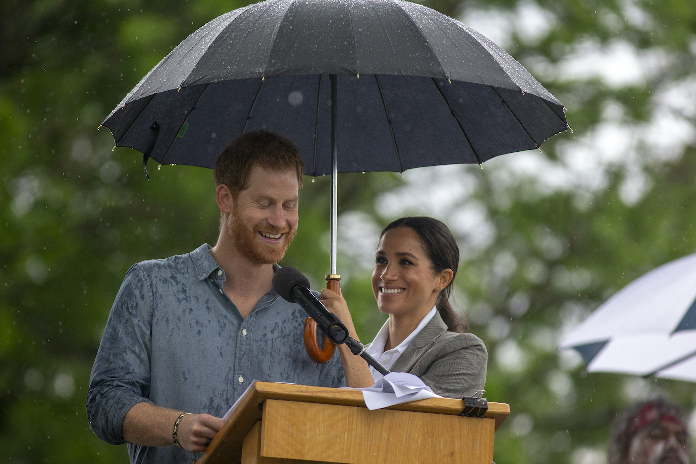 Meghan Markle holds an umbrella for Prince Harry while he gives a speech in Dubbo, Australia