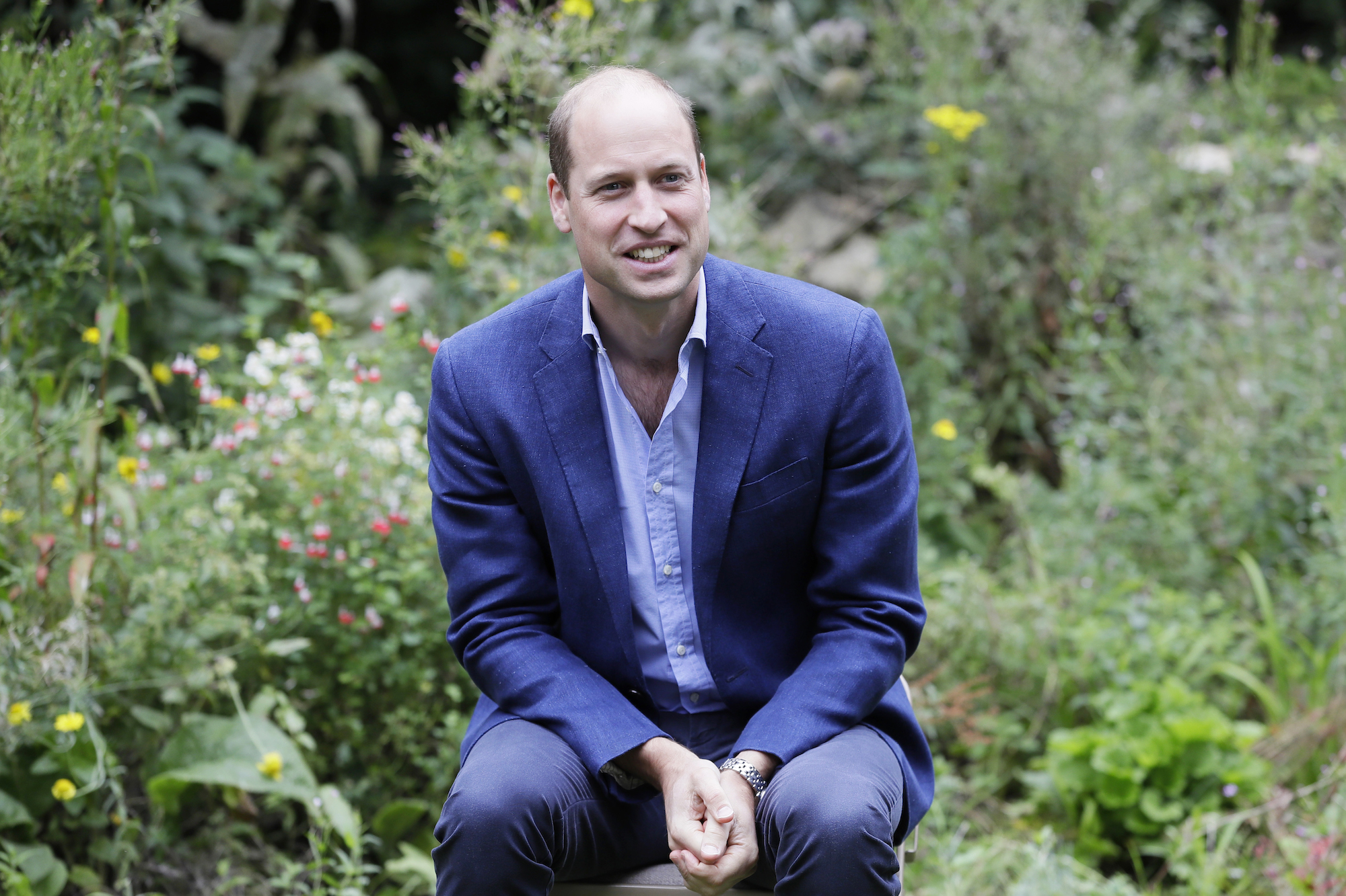 Prince William smiling, seated, in a garden