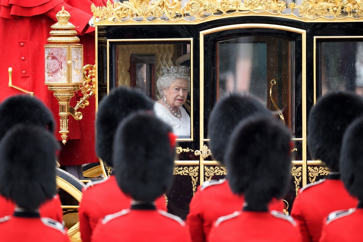 Queen Elizabeth II rides in carriage past guards