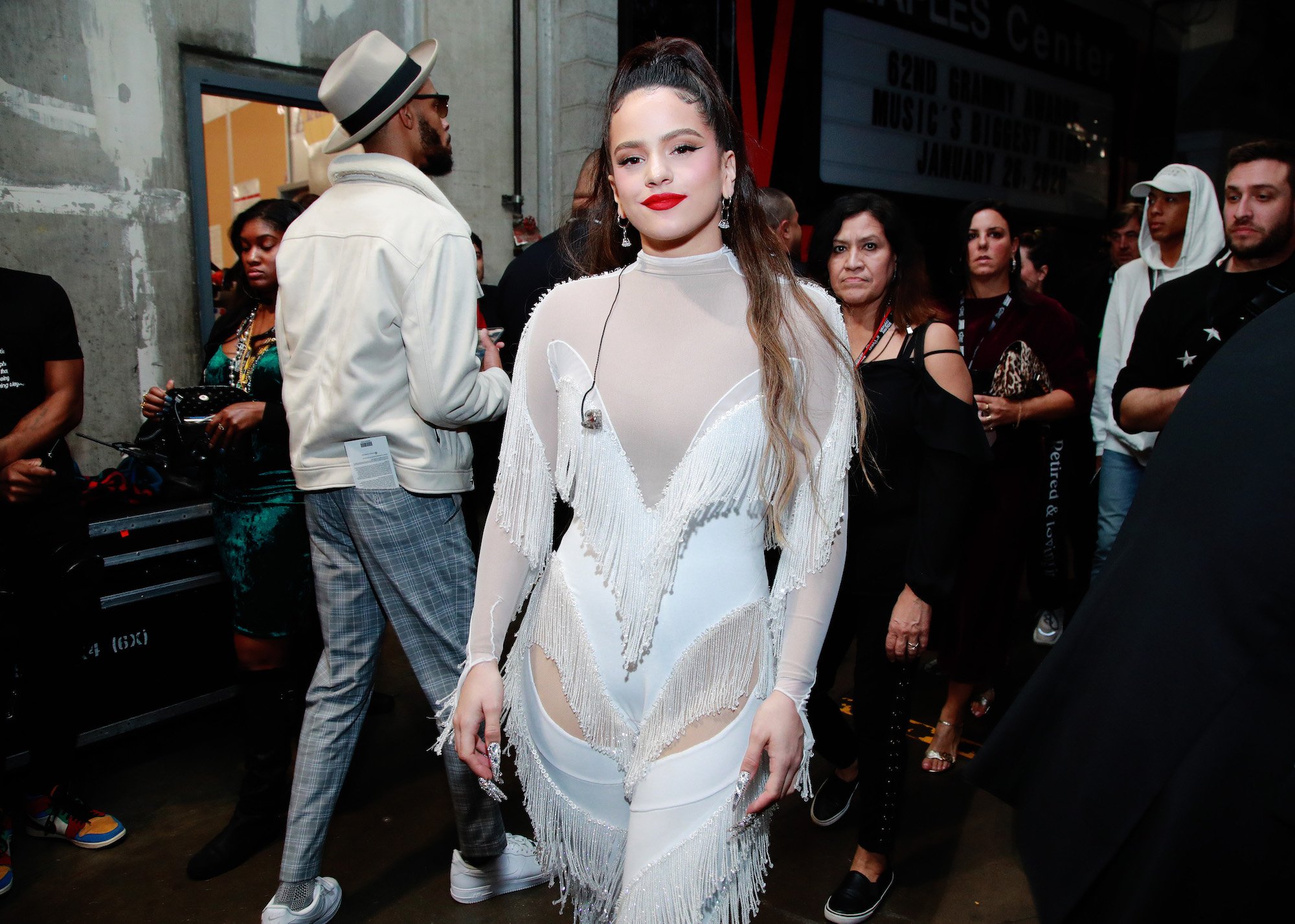 Rosalía smiling at the camera, wearing all white