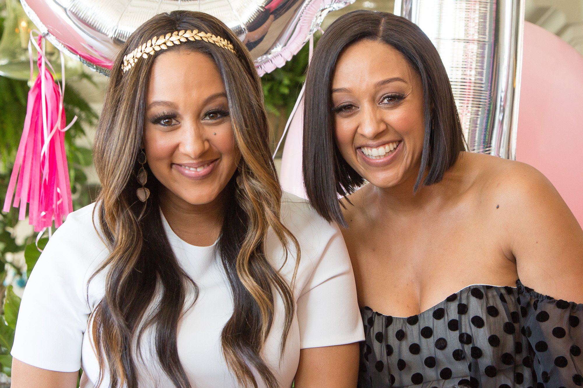 Tamera Mowry-Housley (L) and Tia Mowry smiling at the camera