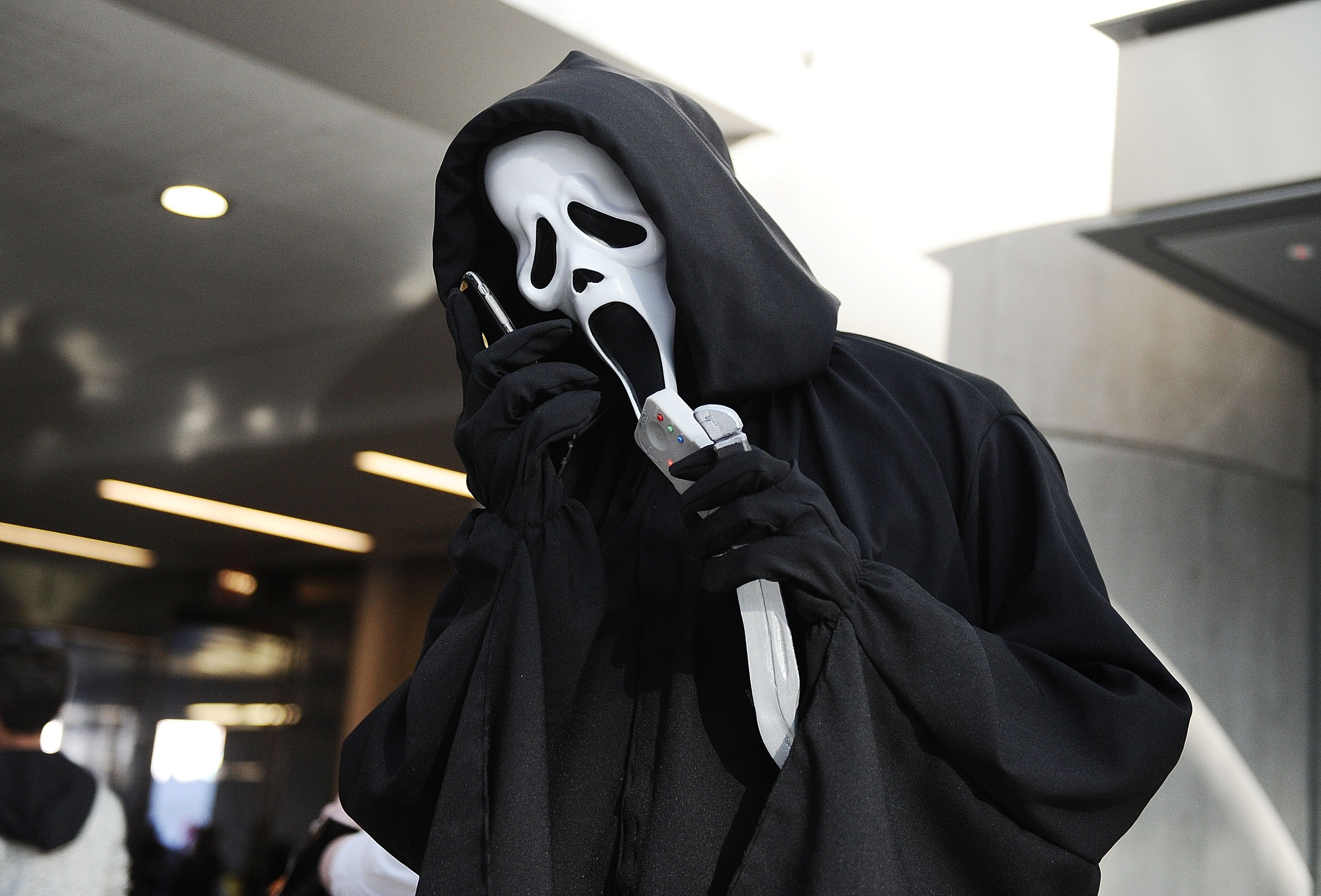 A Ghostface cosplayer with a phone