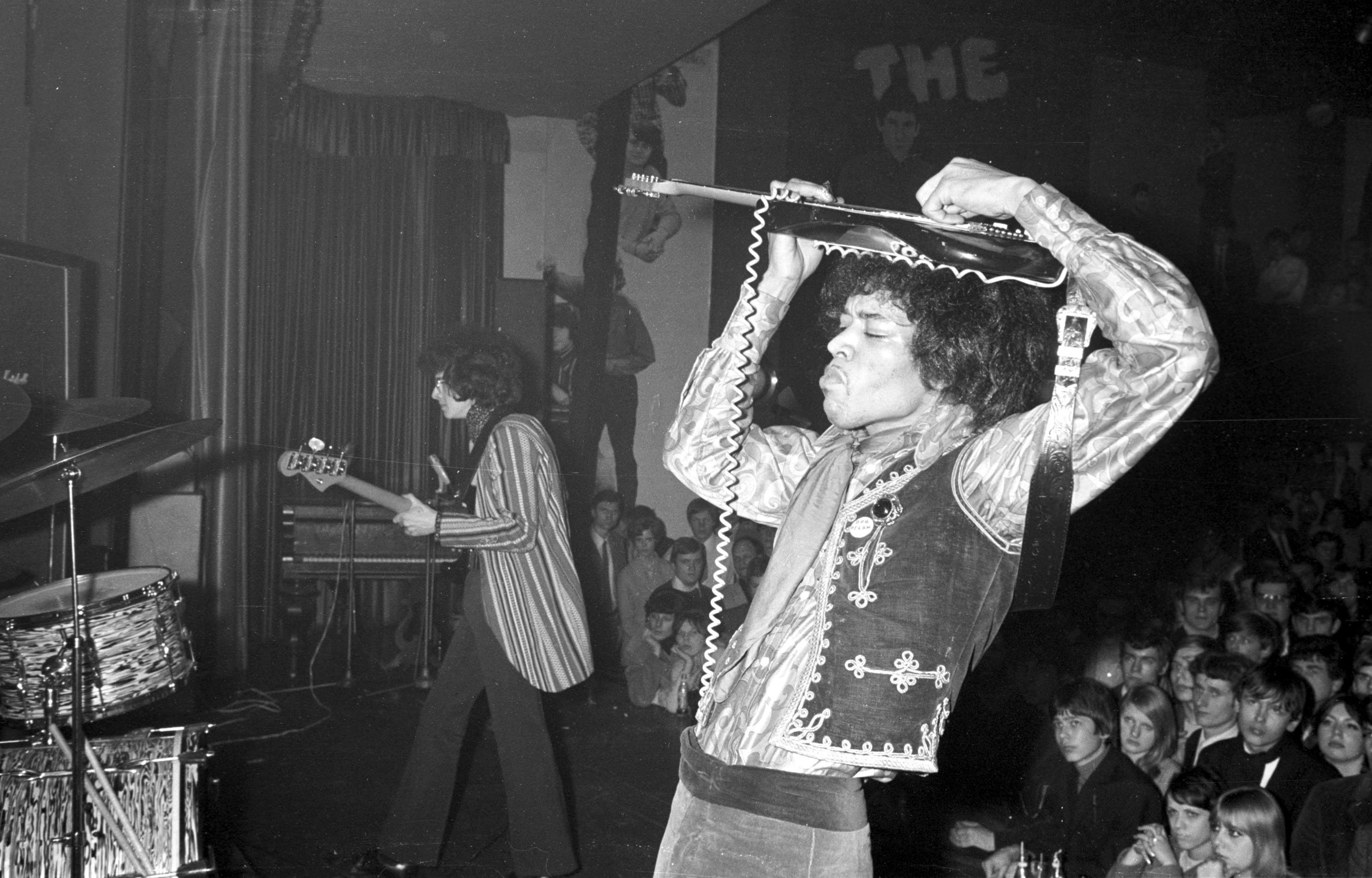 Jimi Hendrix holding his guitar above his head