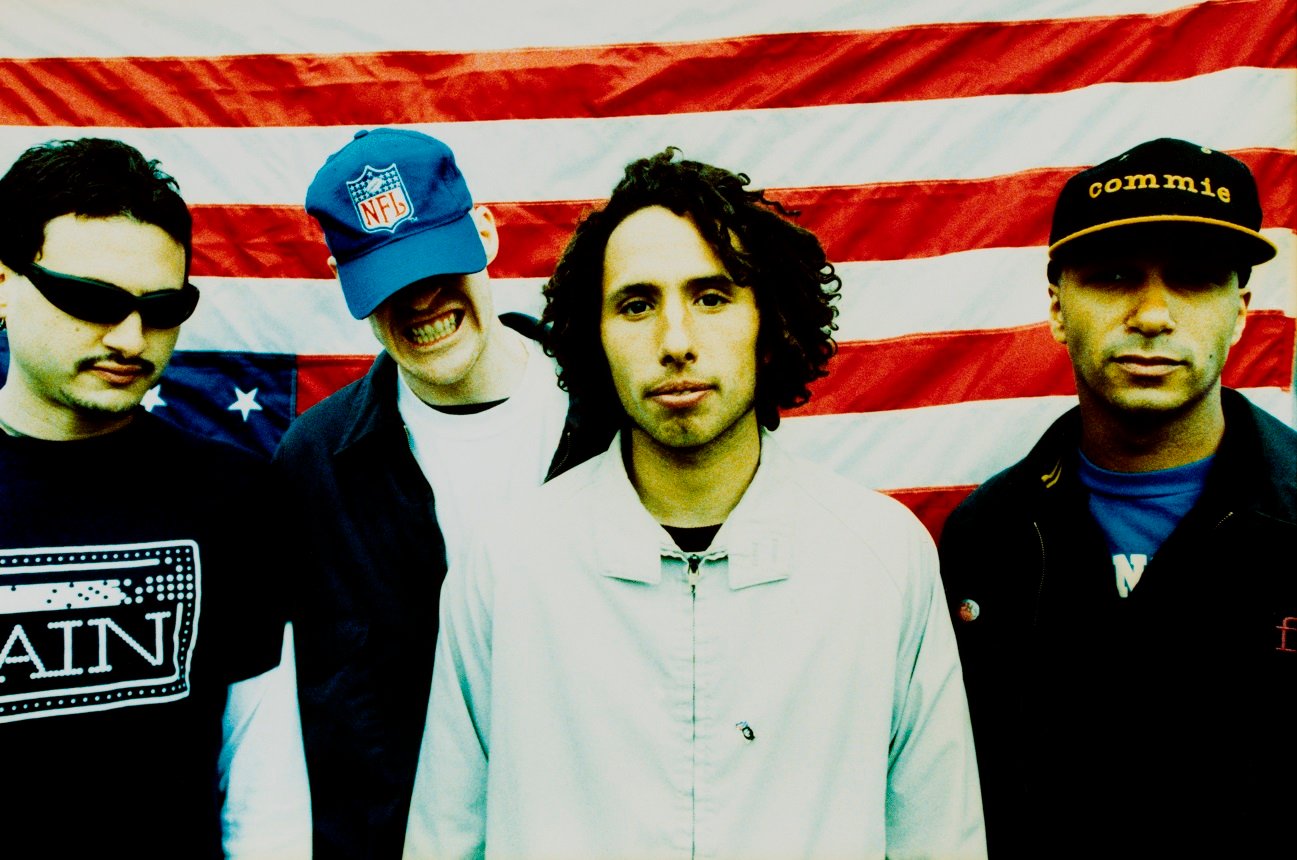 Rage Against the Machine posed in front of upside-down American flag