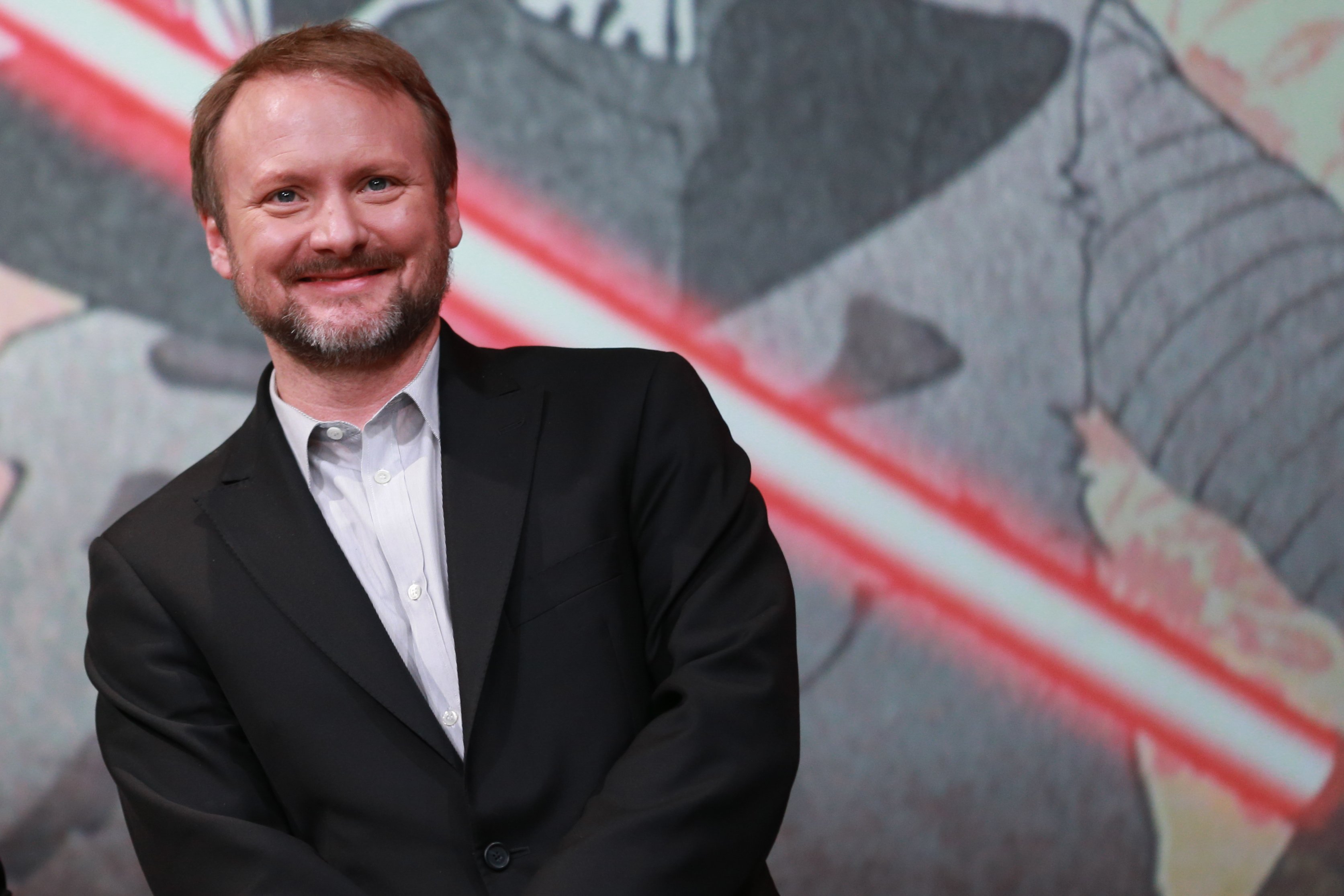 Rian Johnson in front of a Star Wars poster