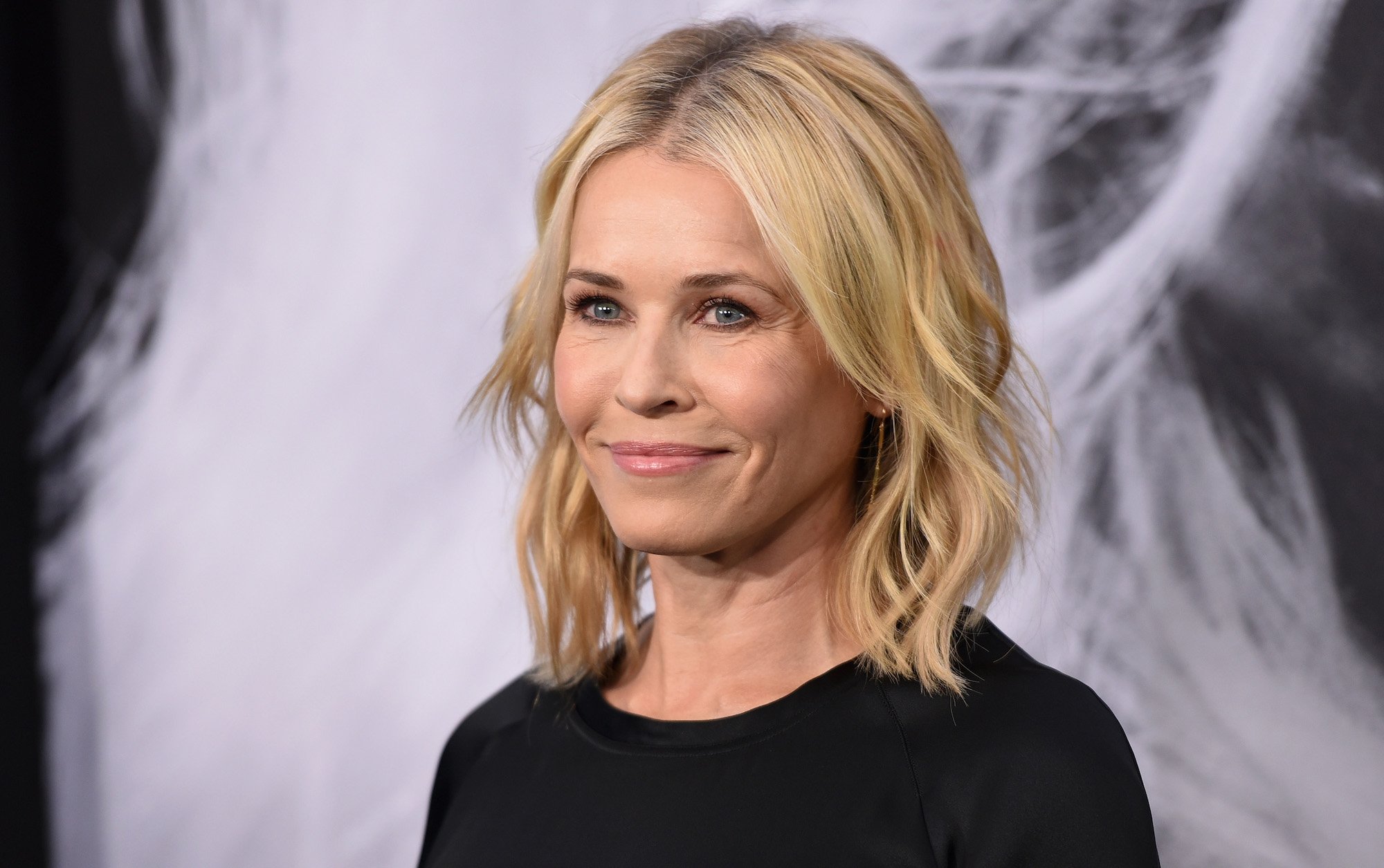 Chelsea Handler smiling in front of a blurred background