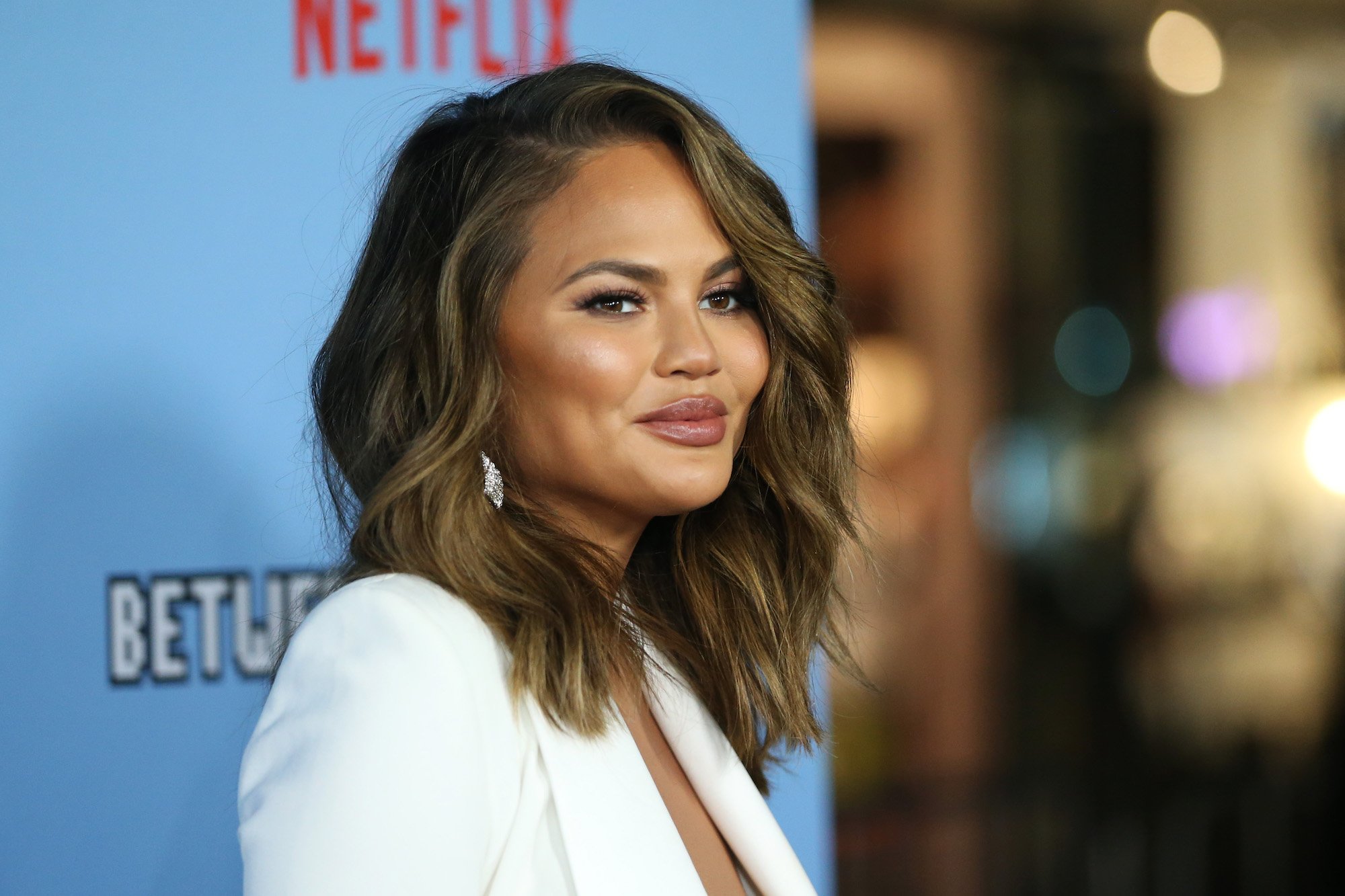Chrissy Teigen smiling in front of a blurred background
