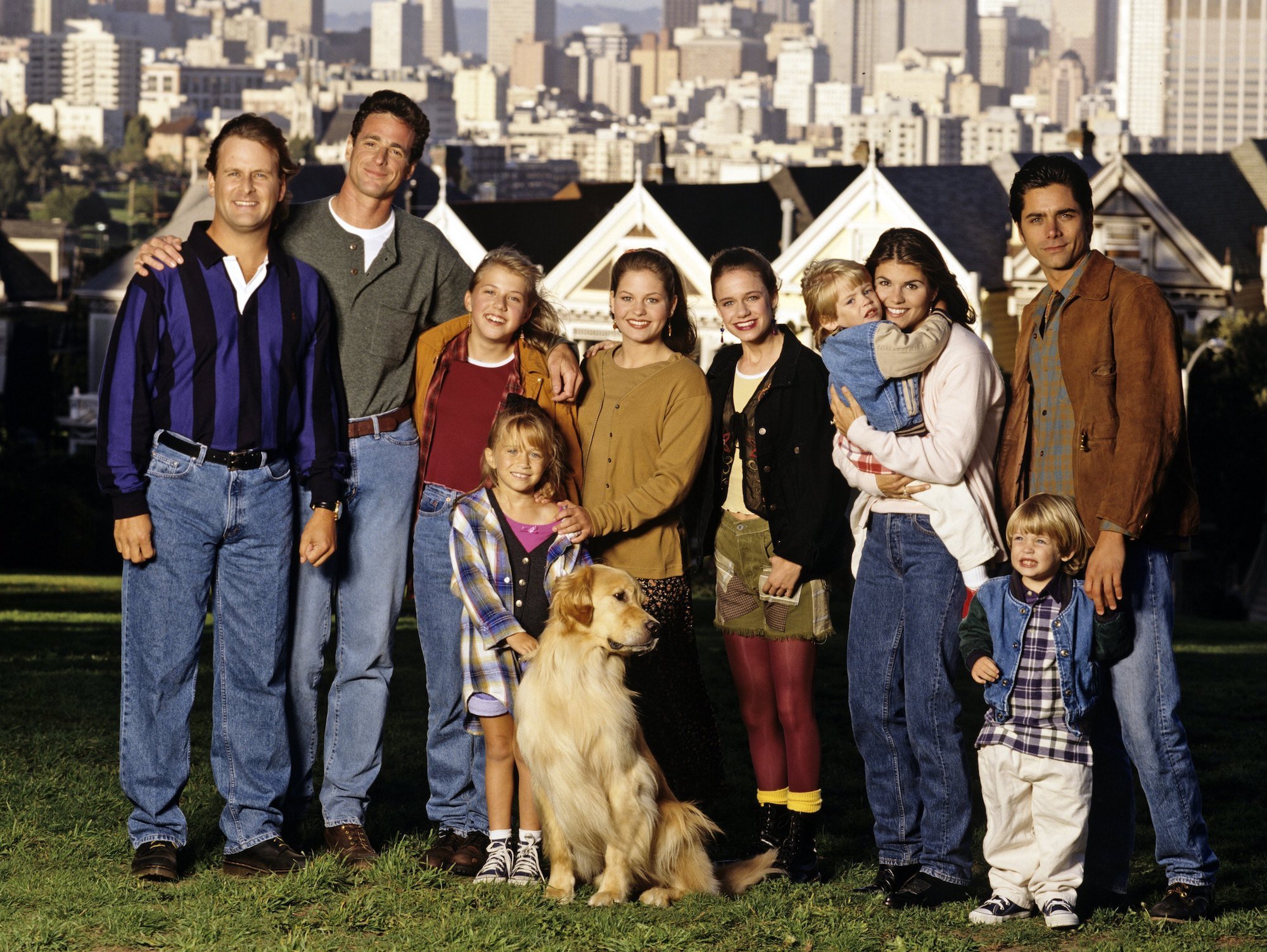 (L-R) Dave Coulier (Joey), Bob Saget (Danny), Jodie Sweetin (Stephanie), Mary Kate Olsen (Michelle), Candace Cameron (D.J.), Andrea Barber (Kimmy), Blake Tuomy-Wilhoit (Nicky), Lori Loughlin (Rebecca), Dylan Tuomy-Wilhoit (Alex), John Stamos (Jesse) smiling in front of the famed 'Full House' houses