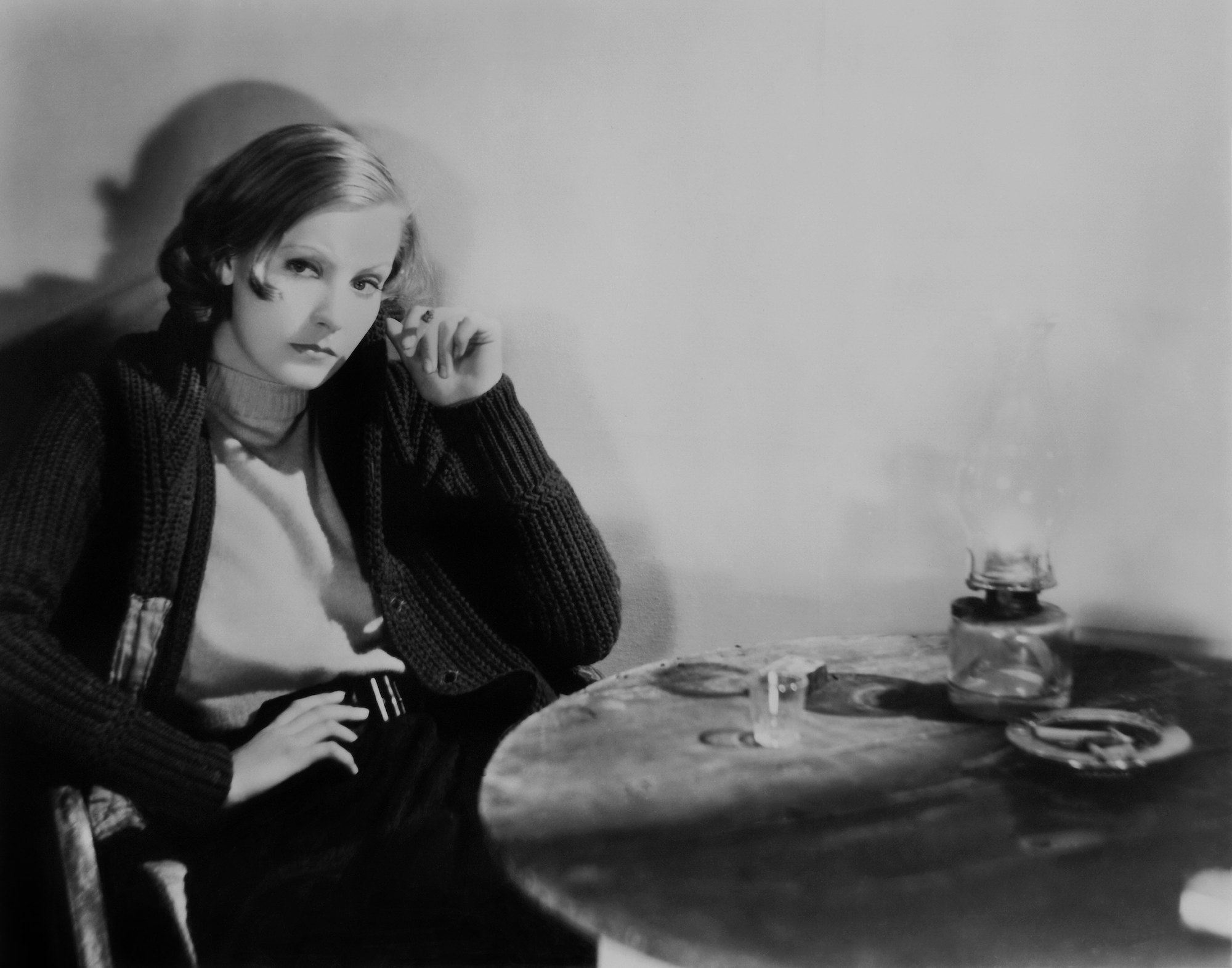 Greta Garbo on set of 'Anna Christie' looking off camera, sitting at a table