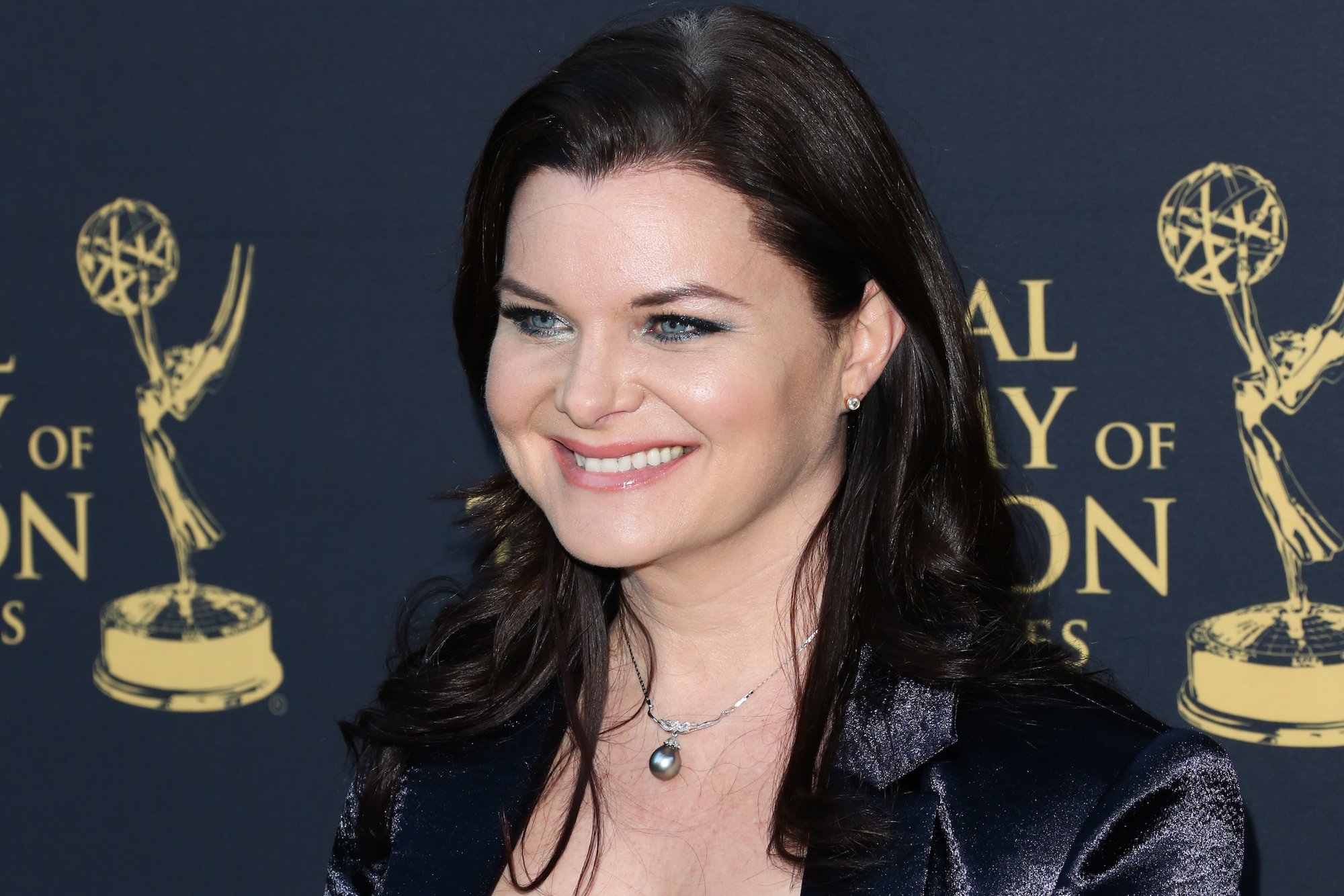 Heather Tom smiling in front of a blue background