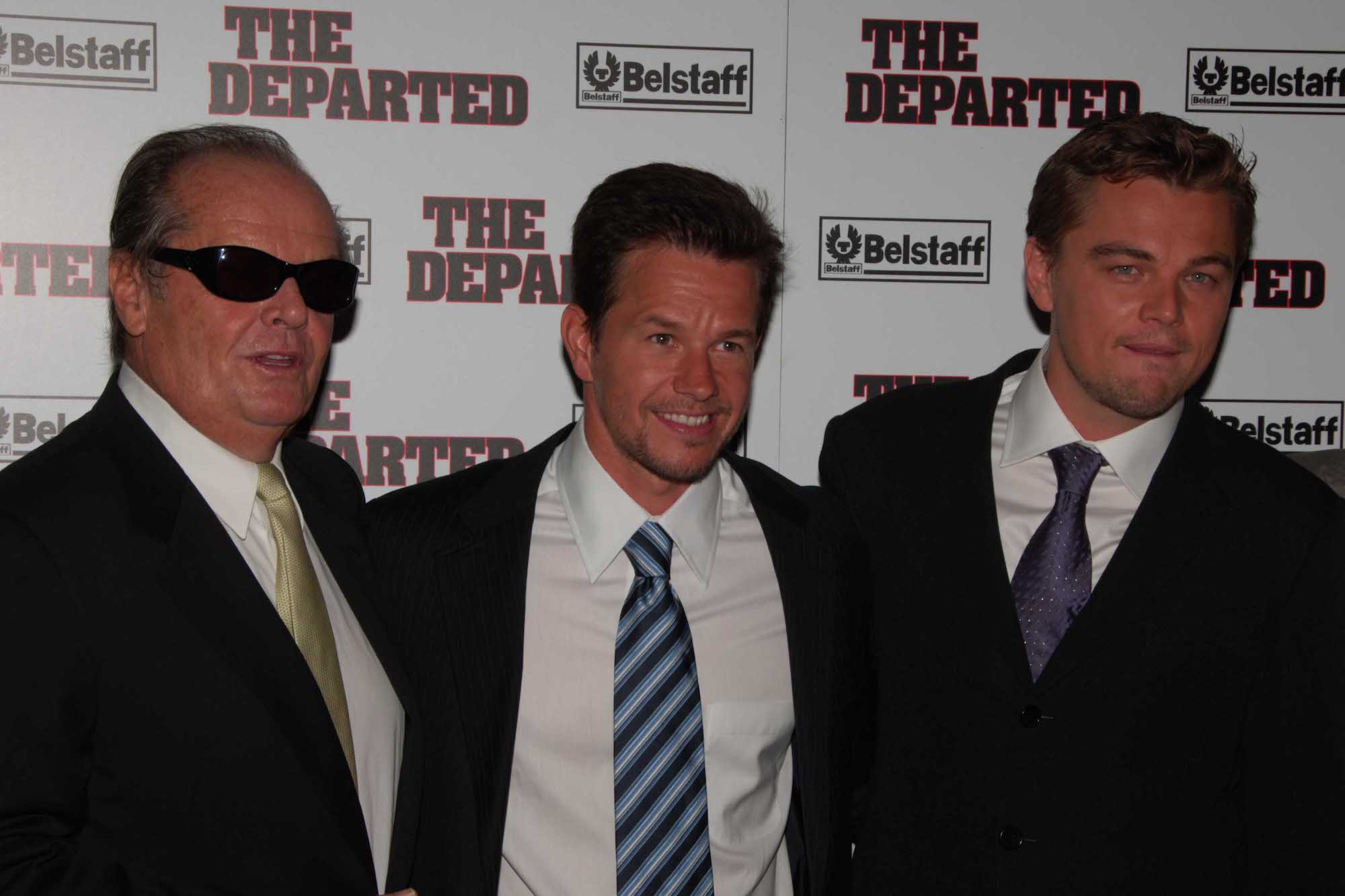(L-R) Jack Nicholson, Mark Wahlberg, and Leonardo DiCaprio smiling in front of a white background
