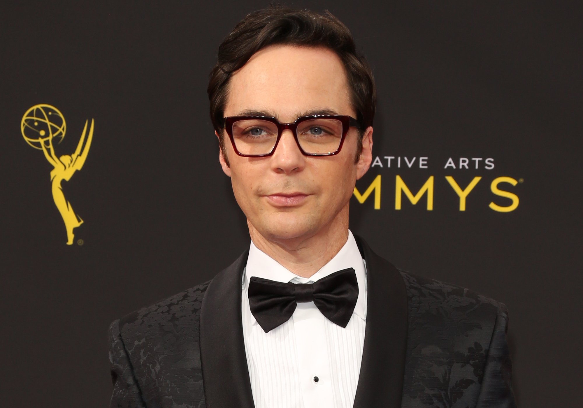 Jim Parsons smiling slightly in front of a black background