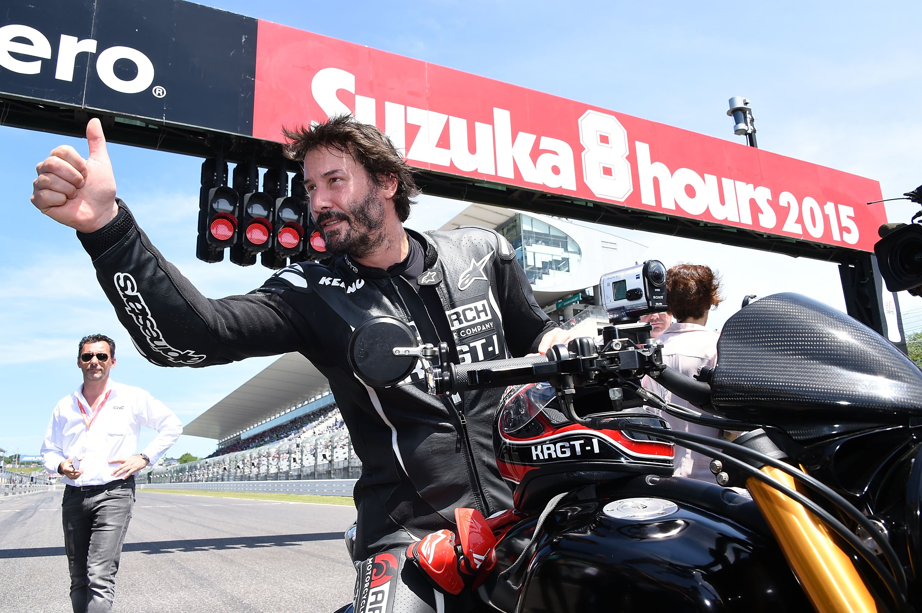 Keanu Reeves giving a thumbs up while sitting on a motorcycle