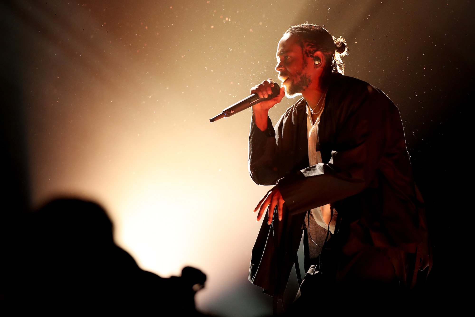 Kendrick Lamar singing into a microphone, photographed from the side