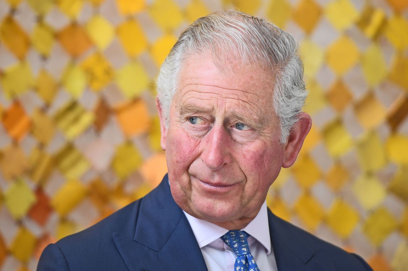Prince Charles looking to the side in front of a yellow background