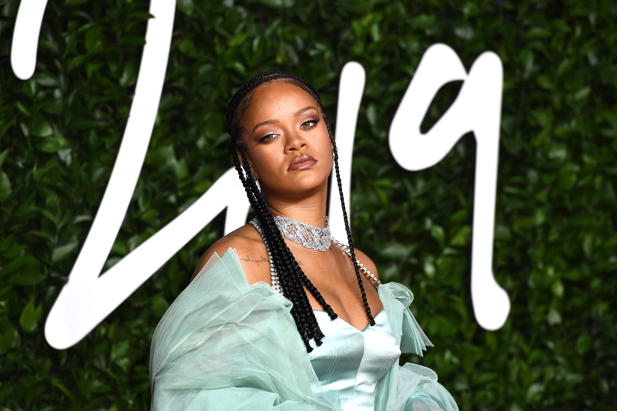 Rihanna looking at the camera in front of a green background