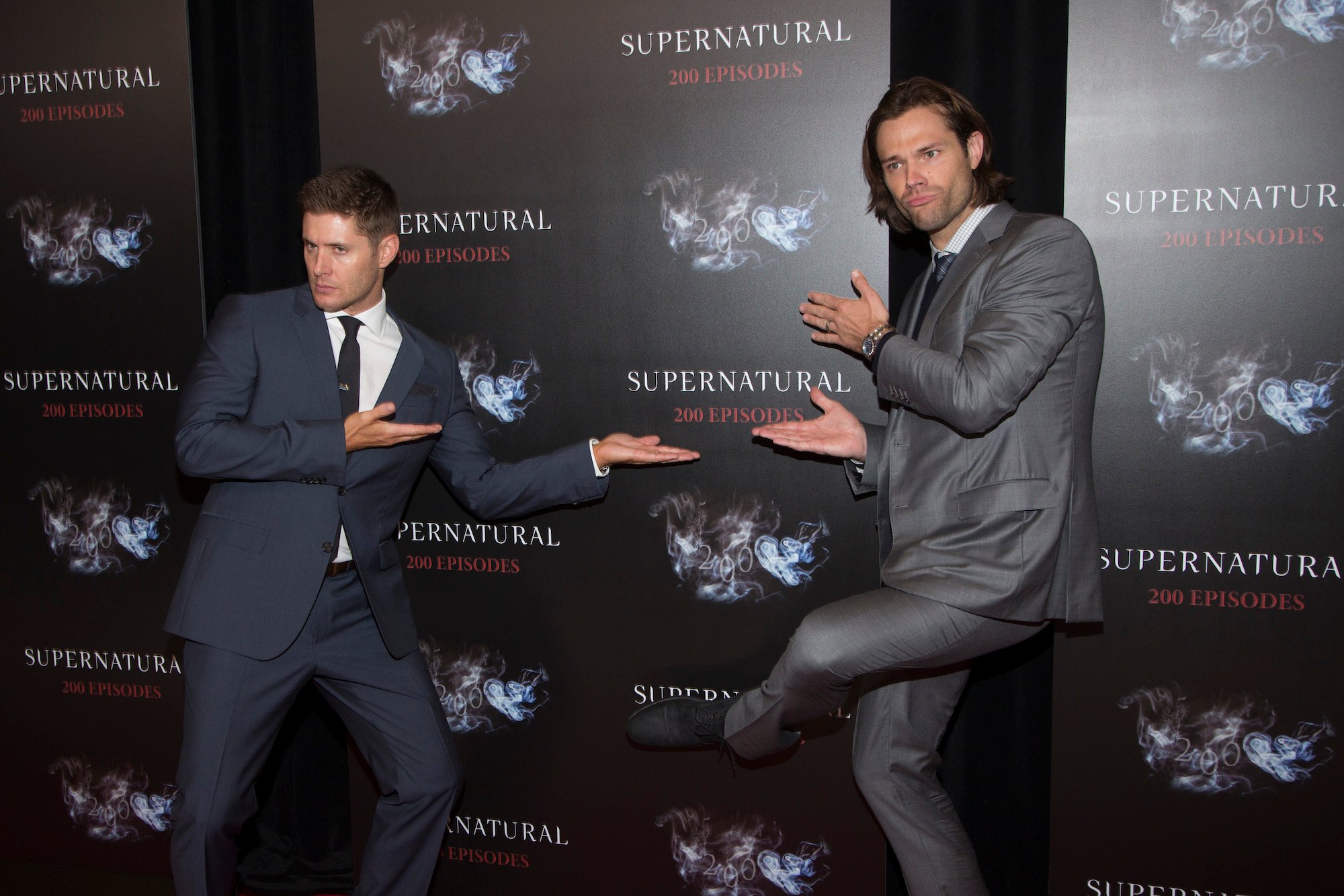 Jensen Ackles and Jared Padalecki striking a silly pose in front of a black background