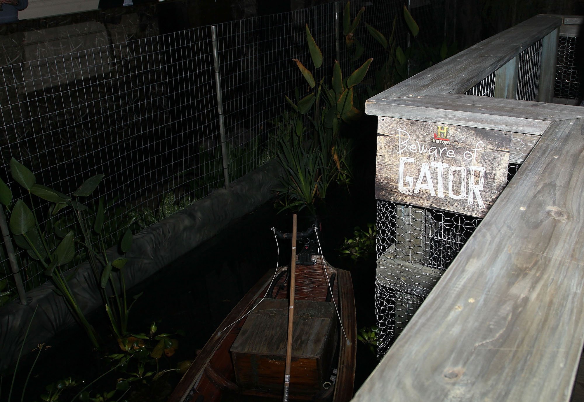 A staged 'swamp' with a boat in it, under a sign saying 'Beware of Gator'