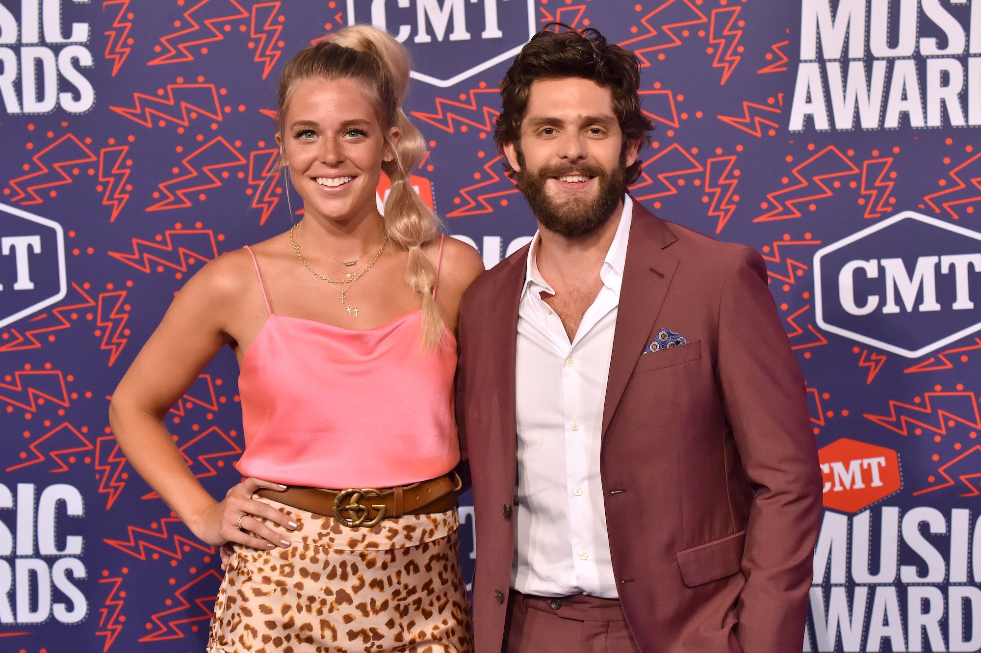 (L-R) Laura Atkins and Thomas Rhett smiling in front of a blue background