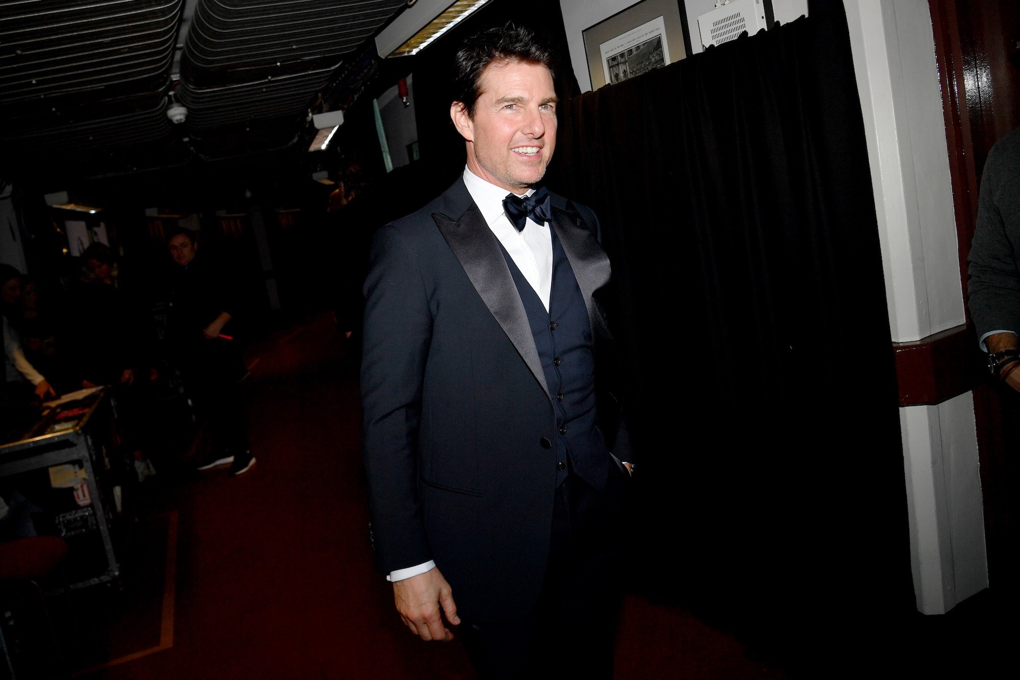 Tom Cruise smiling walking down a hallway