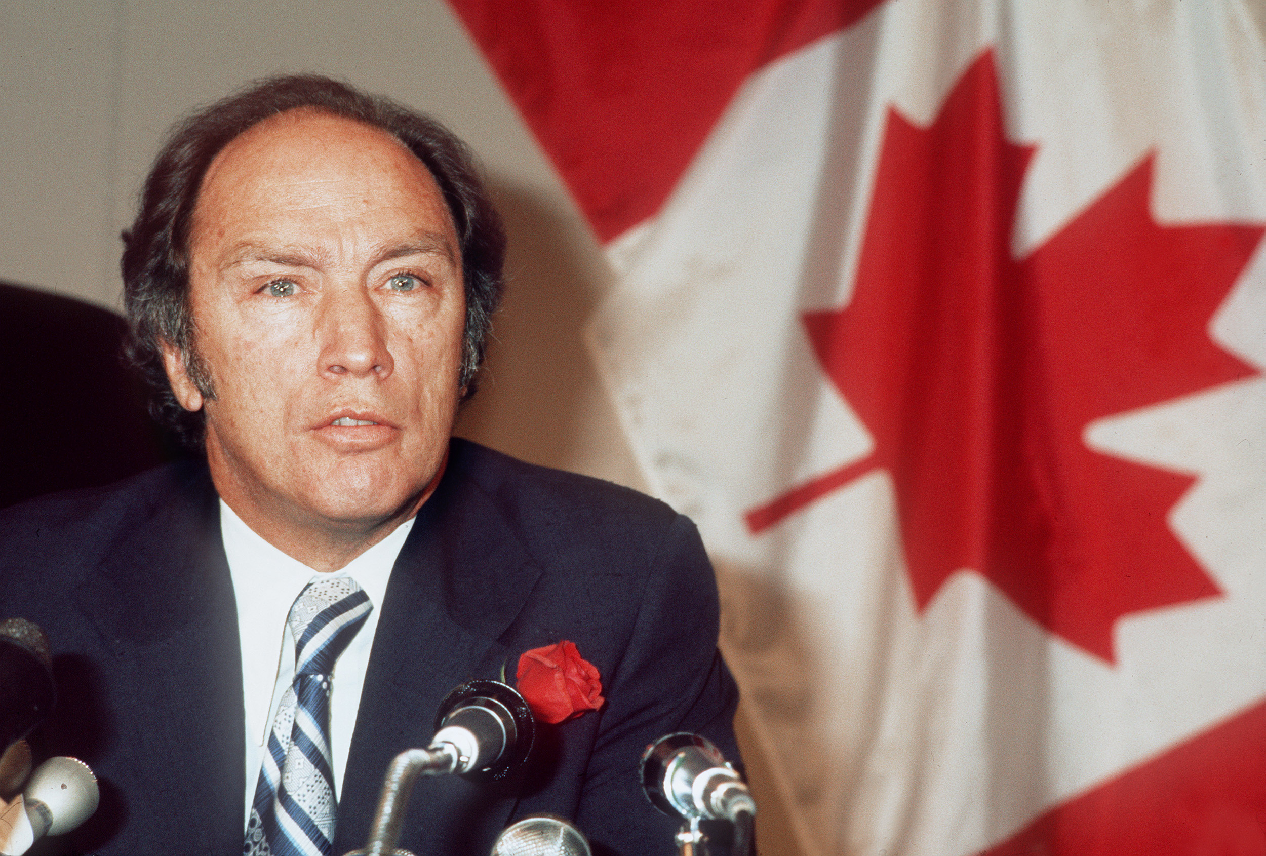 Canadian Prime Minister Pierre Trudeau in front of a Canadian flag