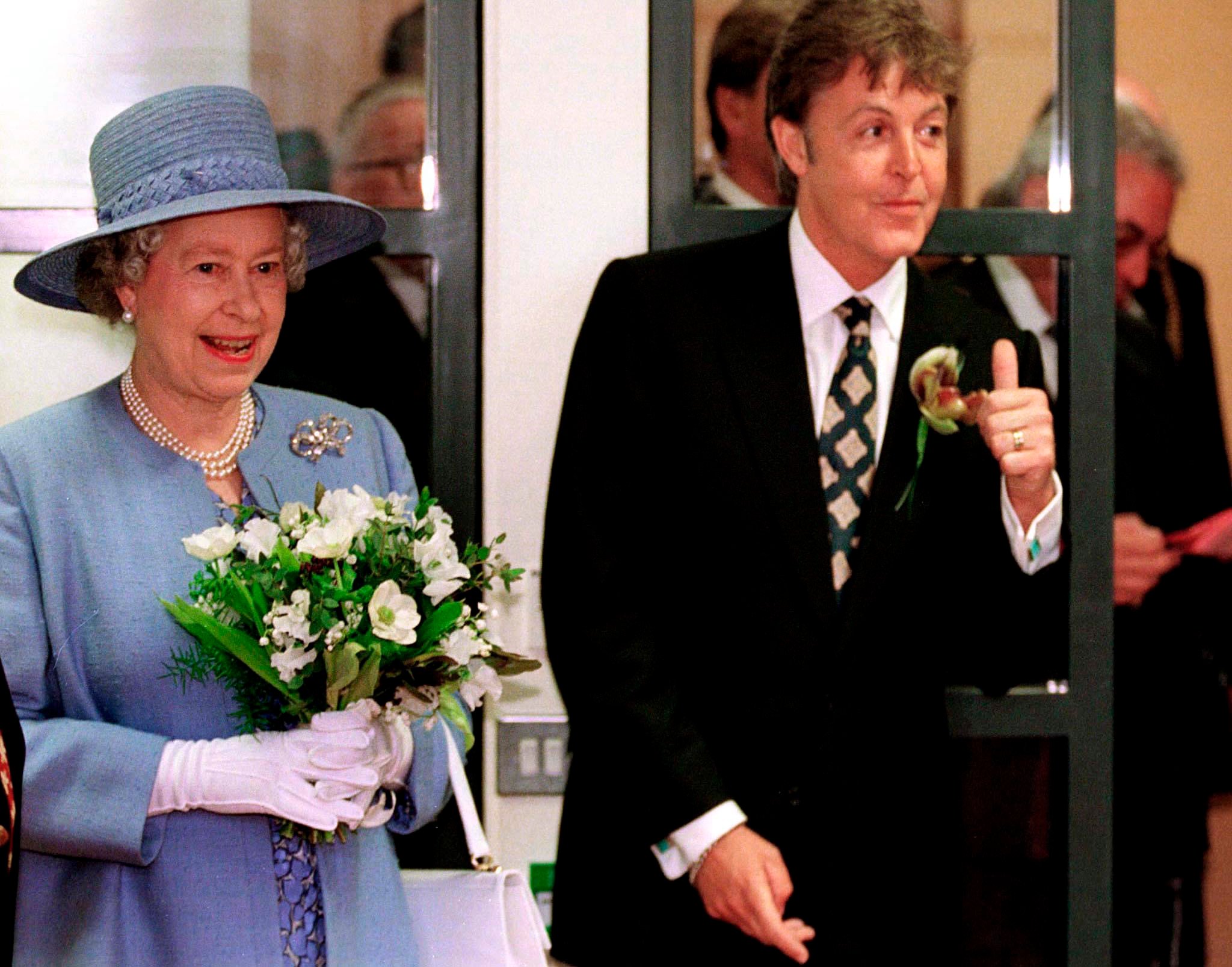 Queen Elizabeth II holding flowers and Paul McCartney wearing a suit