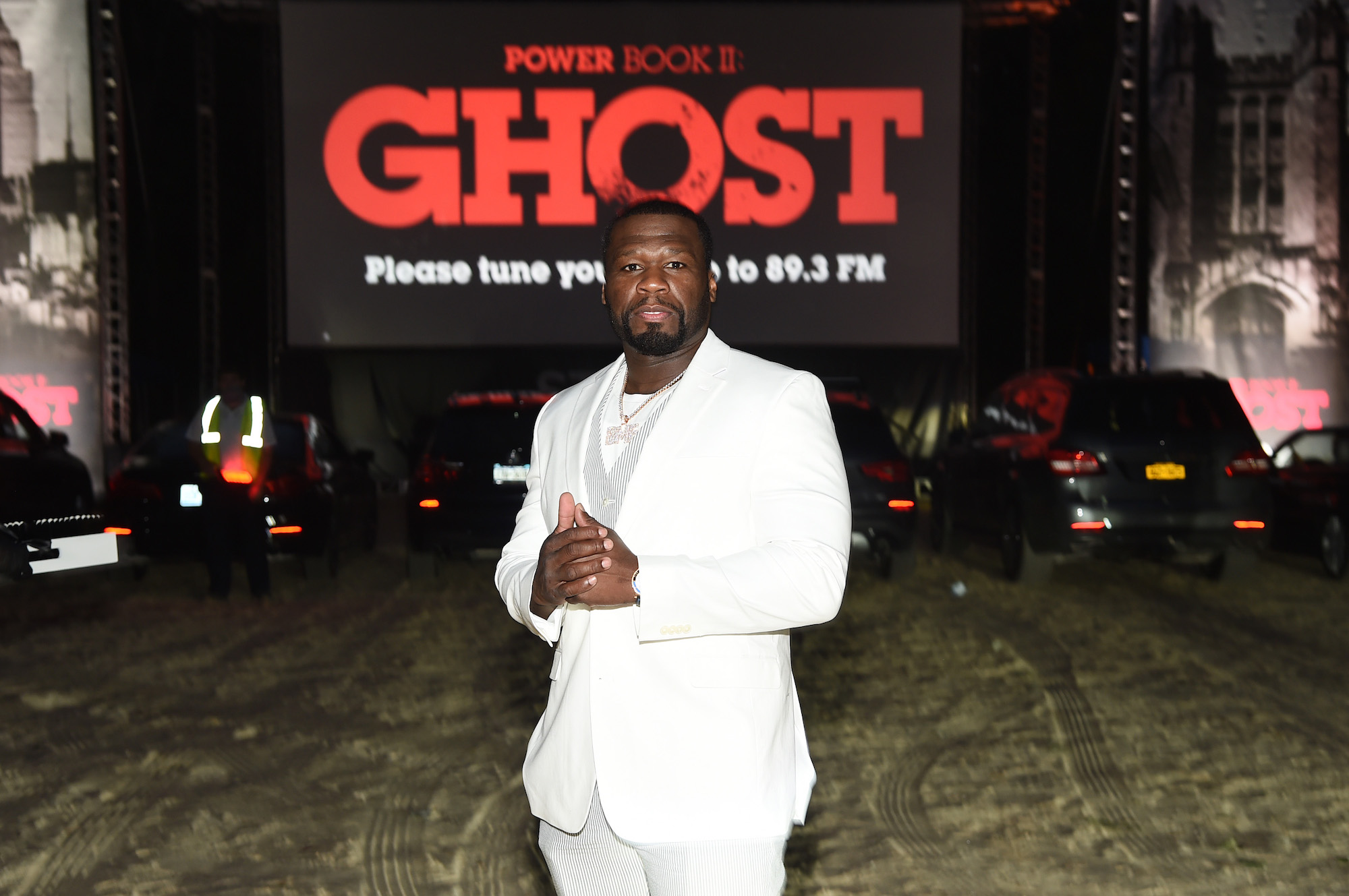 50 Cent holding his hands together in front of a screen with red lettering