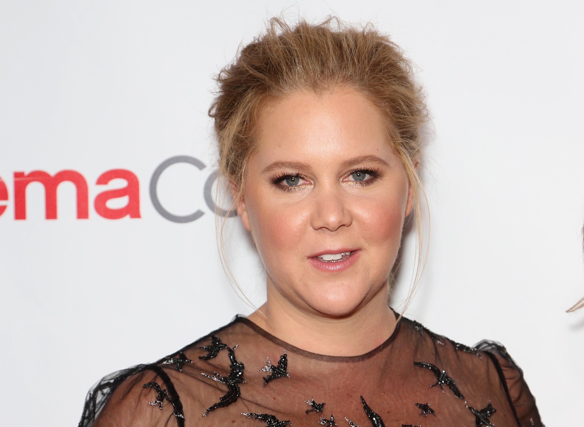 Amy Schumer smiling in front of a white background