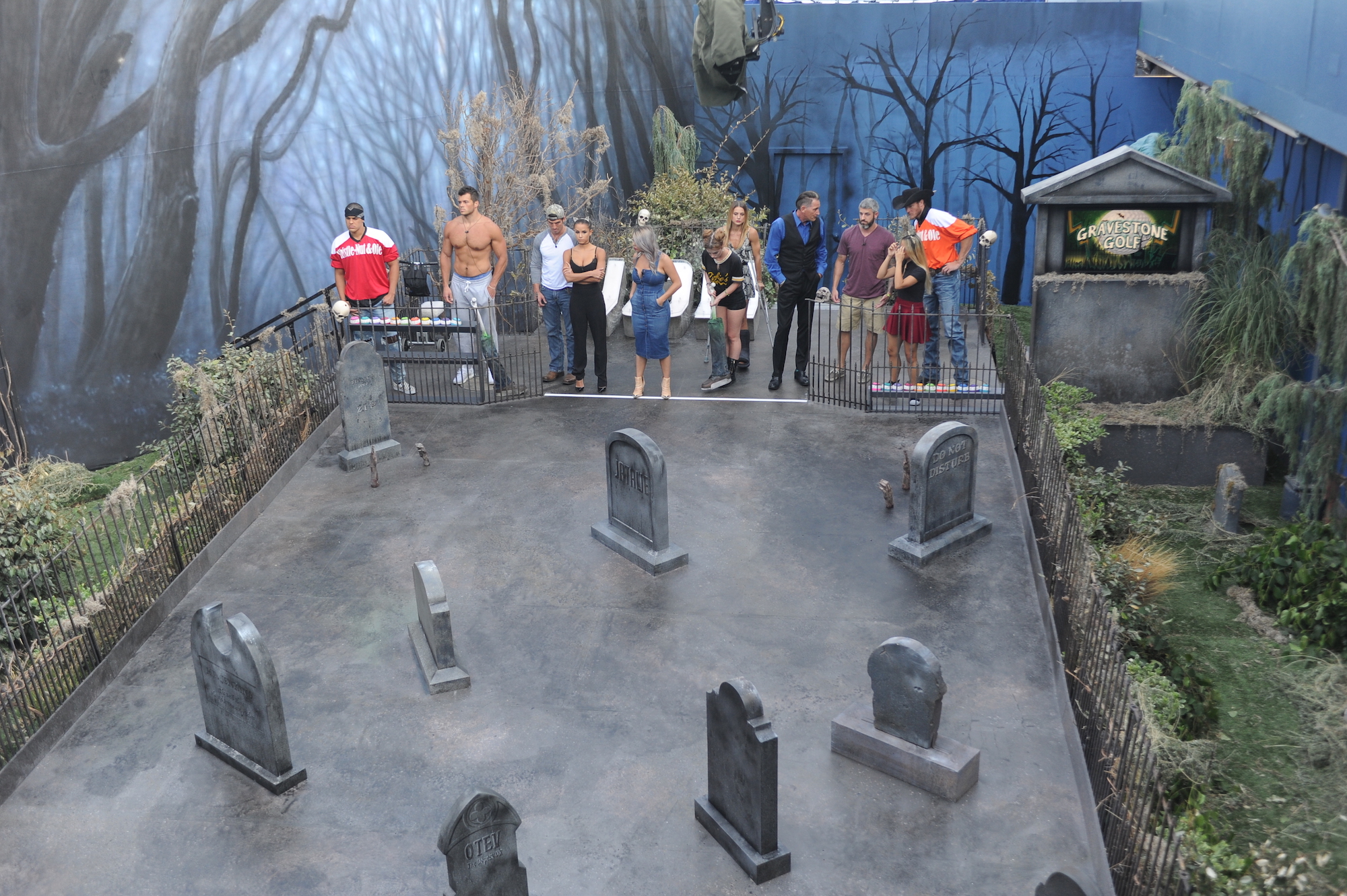 Big Brother contestants standing at the gates of a cemetery set