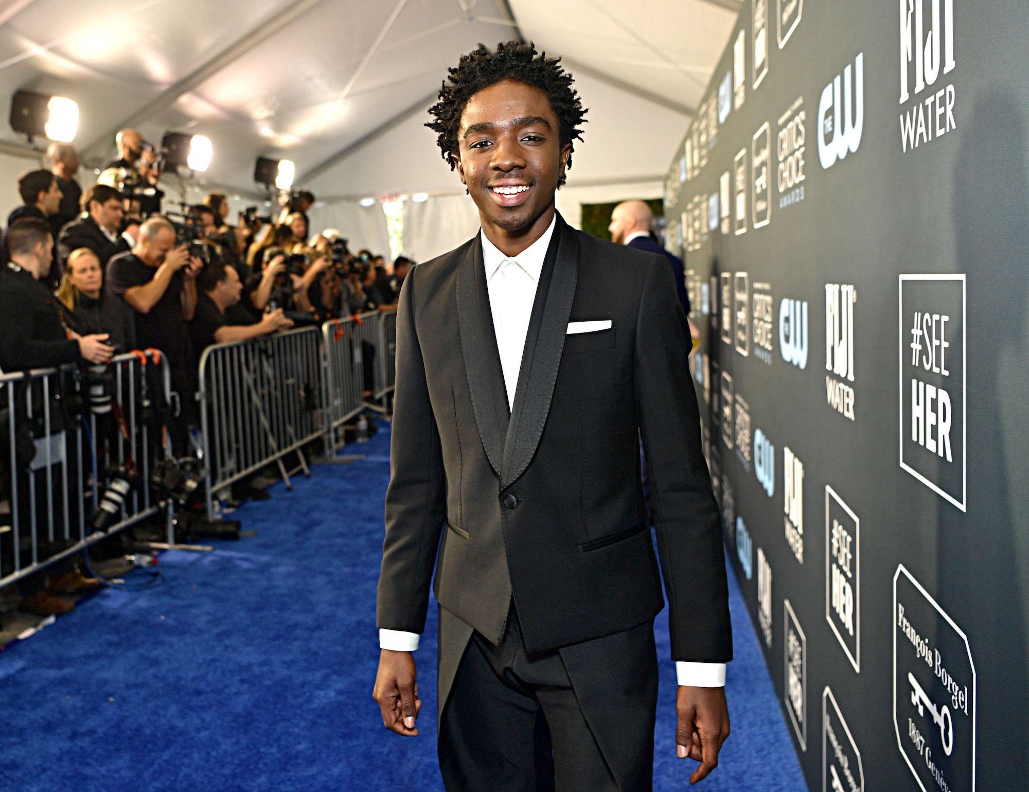 Caleb McLaughlin smiling on a blue carpet