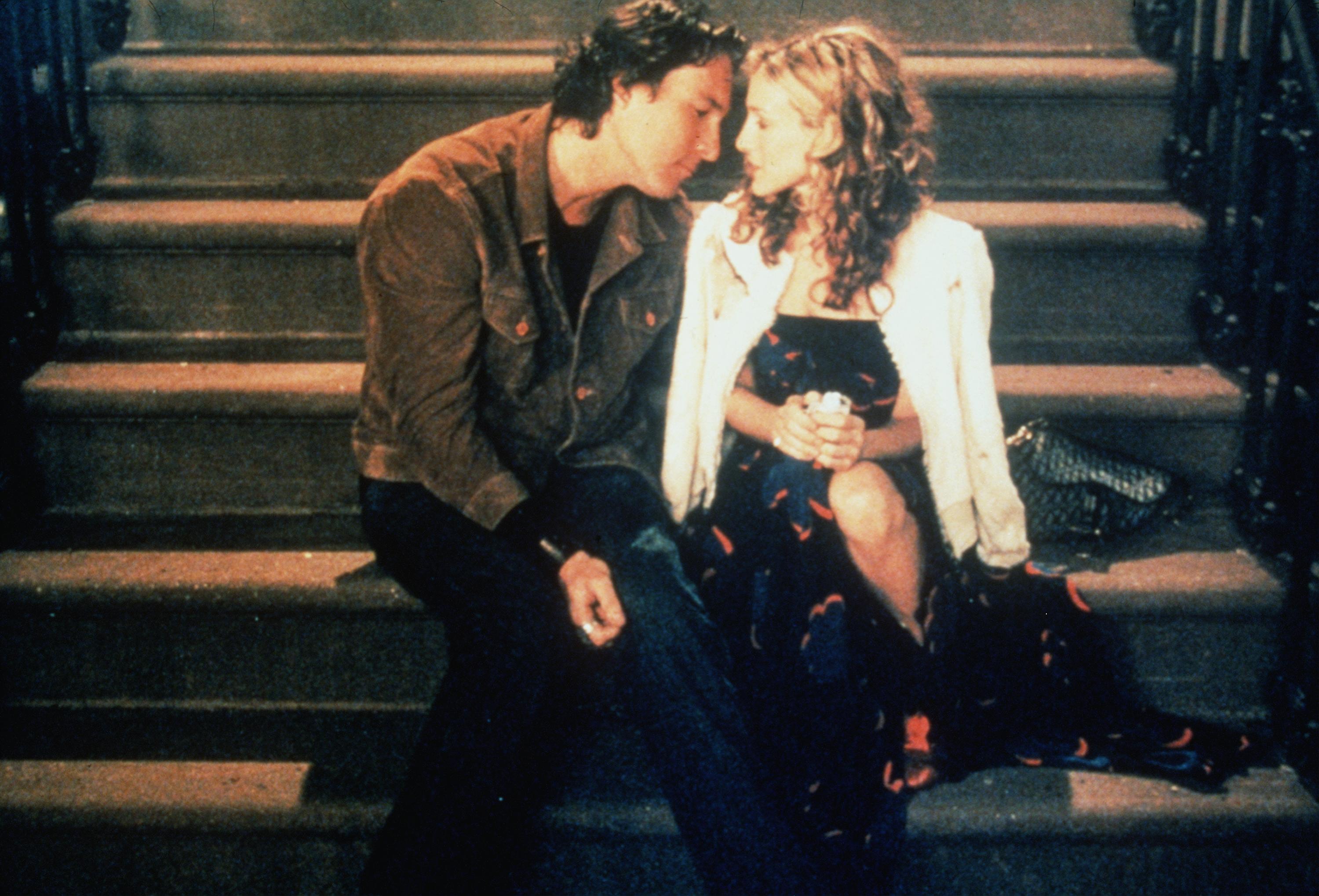 Sarah Jessica Parker as Carrie Bradshaw and John Corbett as Aidan Shaw sit on Carrie's front steps 
