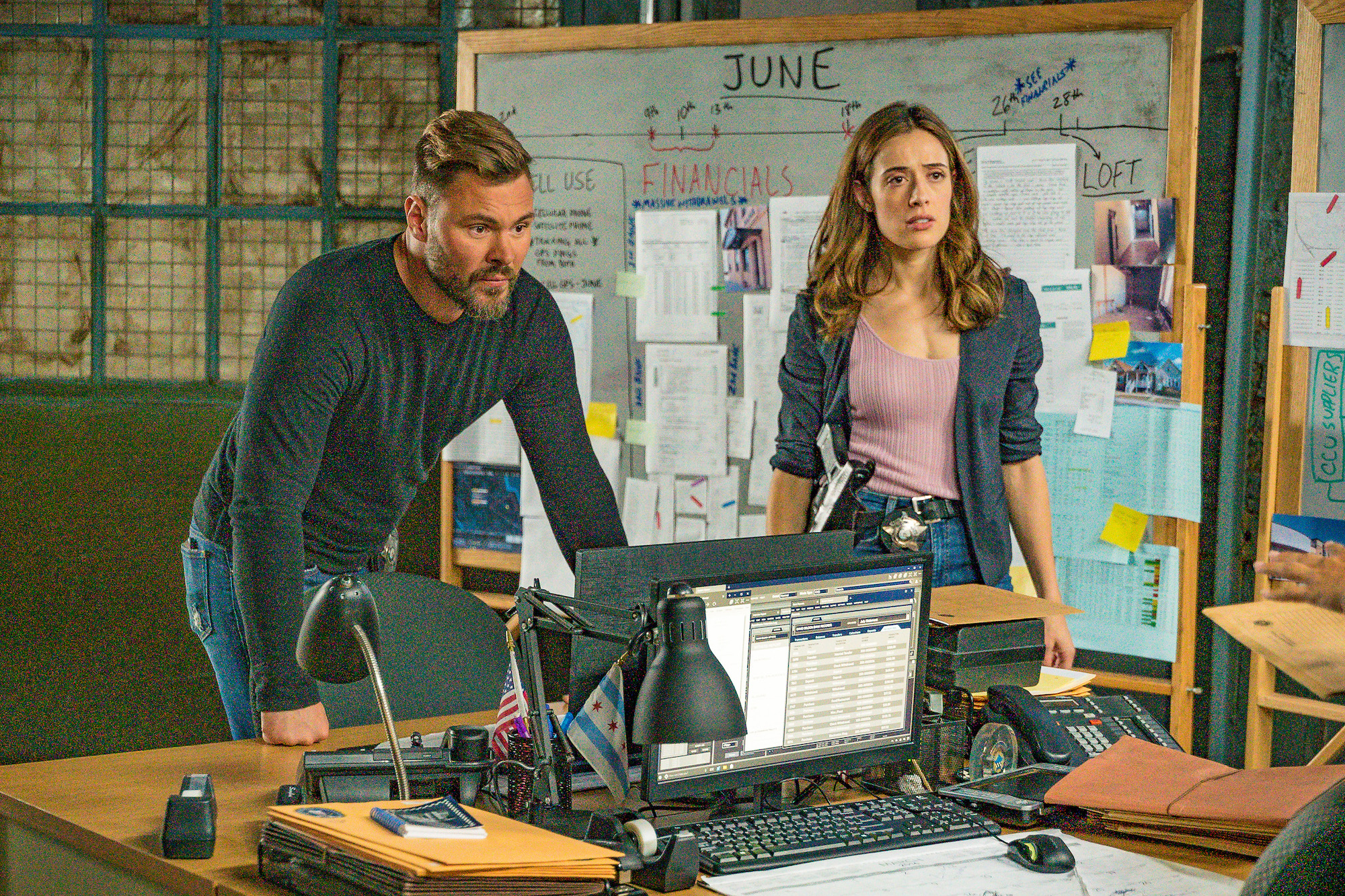 (L-R) Patrick John Flueger as Officer Adam Ruzek, Marina Squerciati as Officer Kim Burgess on 'Chicago P.D.' standing in front of a whiteboard and behind a desk