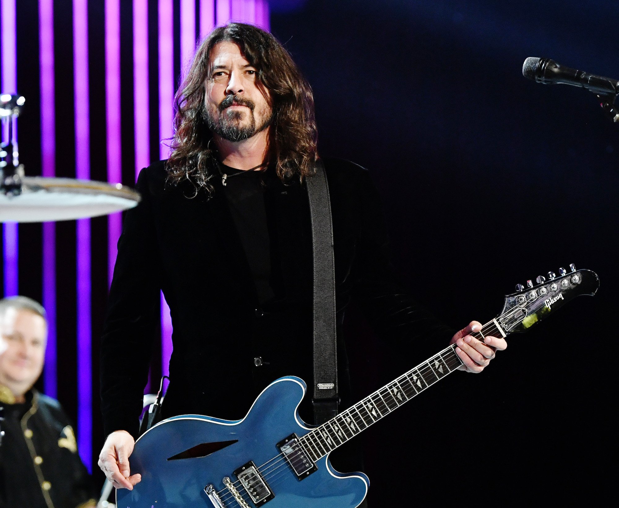 Dave Grohl slightly smiling on stage holding a guitar